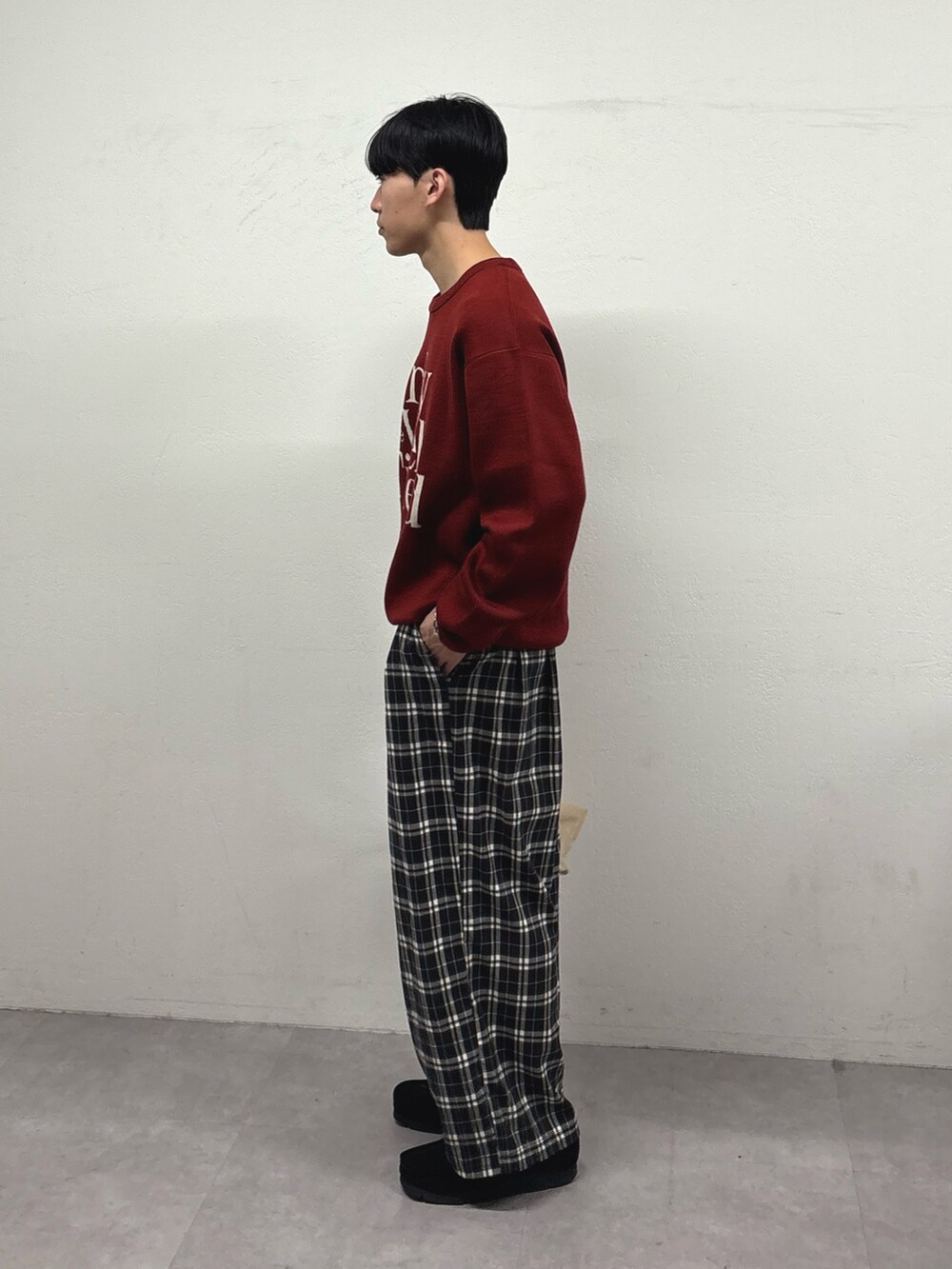 レッド系のニット/セーター、ブラック系のその他パンツ、ブラック系のスニーカーを着用したメンズの冬コーディネートの2枚目の写真