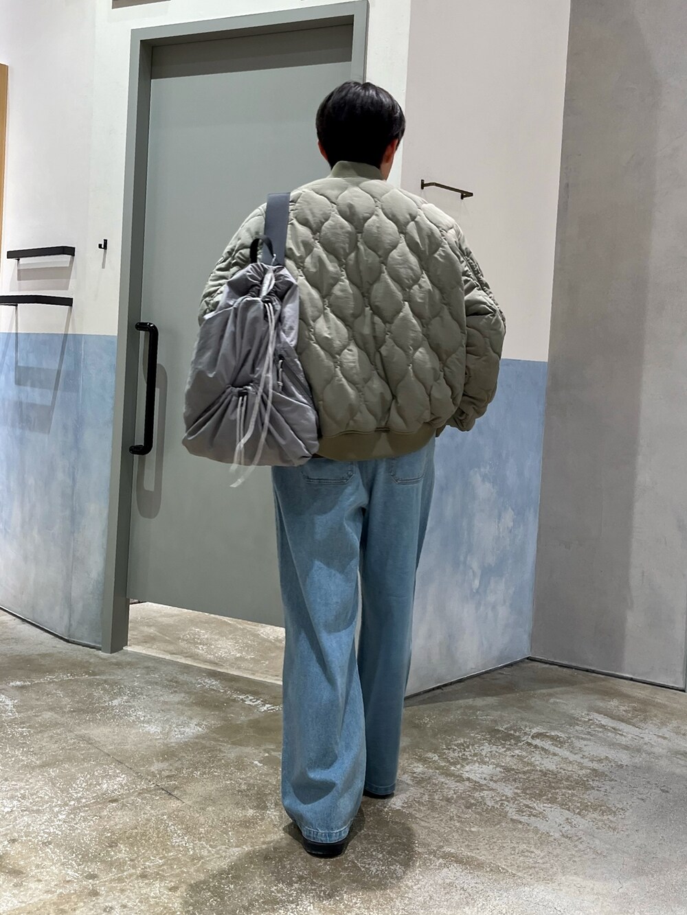 グレー系のショルダーバッグ、グリーン系のMA-1、ブルー系のデニムパンツを着用したメンズの春コーディネートの2枚目の写真