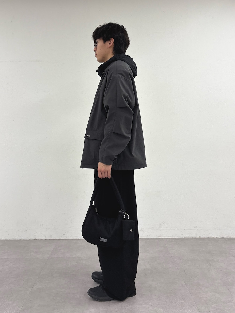 グレー系のテーラードジャケット、ブラック系のパーカー、ブラック系のスラックスを着用したメンズの春コーディネートの2枚目の写真