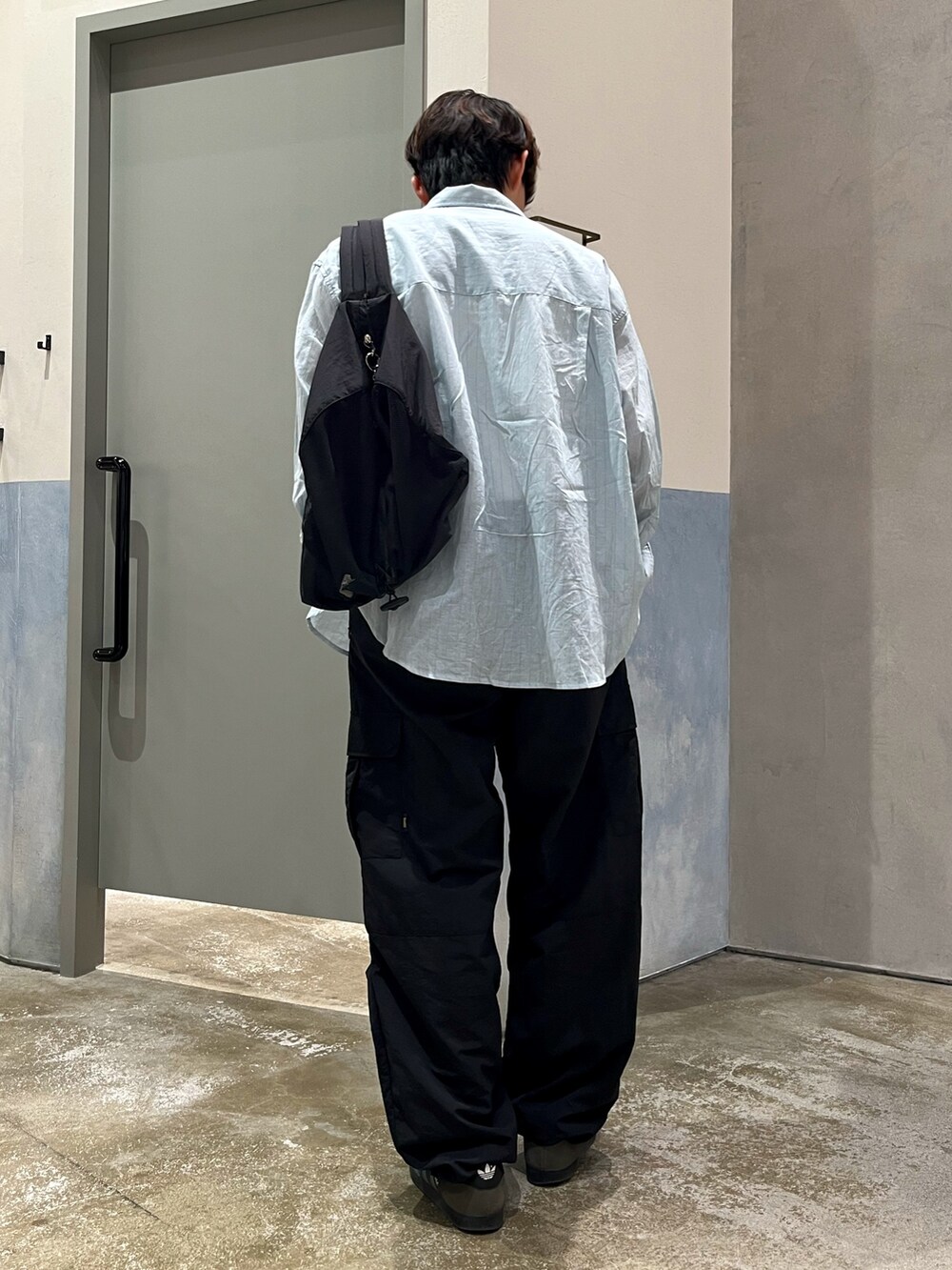 グレー系のスニーカー、ブラック系のカーゴパンツ、ホワイト系のタンクトップを着用したメンズの夏コーディネートの2枚目の写真