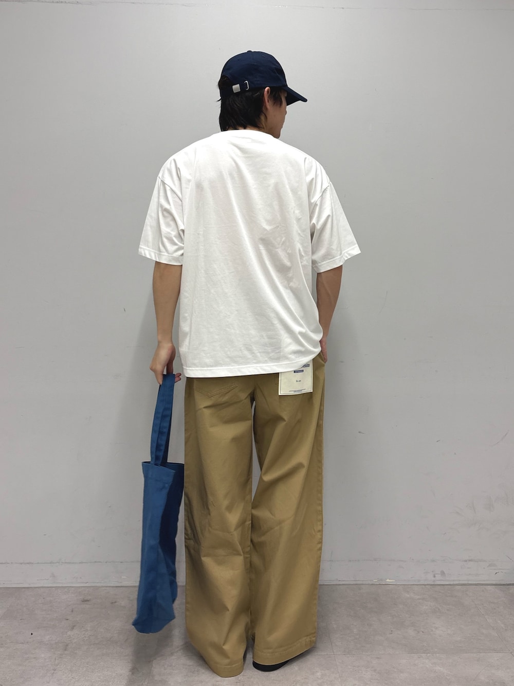 ホワイト系のTシャツ/カットソー、ブルー系のトートバッグ、ベージュ系のデニムパンツを着用したメンズの春コーディネートの3枚目の写真
