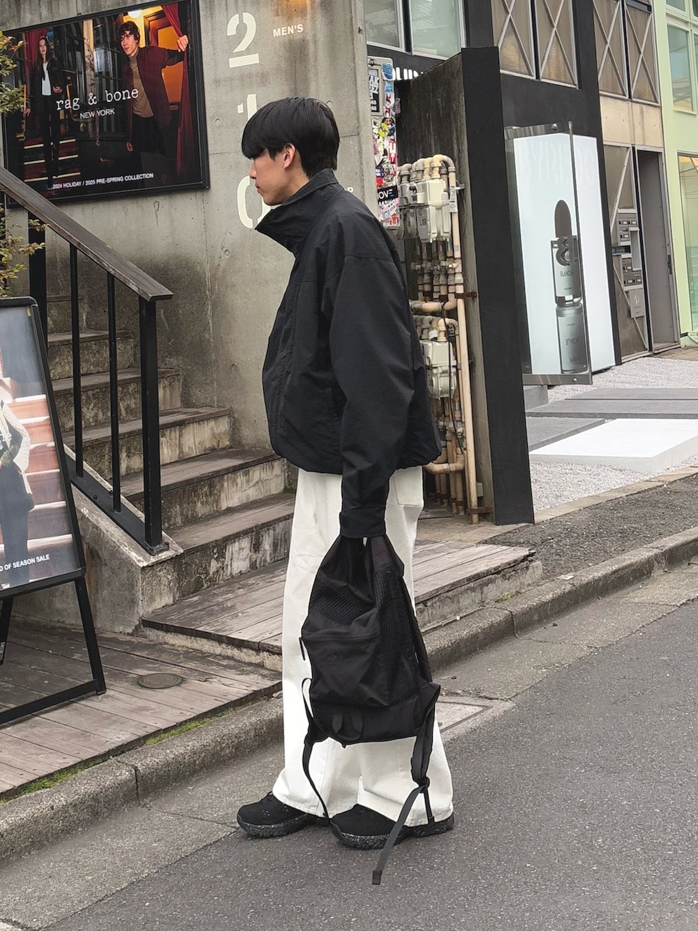 ブラック系のナイロンジャケット、ホワイト系のパンツ、ブラック系のバックパック/リュックを着用したメンズの冬コーディネートの2枚目の写真