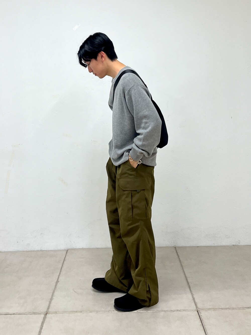 グリーン系のカーゴパンツ、ブラック系のスニーカー、グレー系のニット/セーターを着用したメンズの秋コーディネートの2枚目の写真