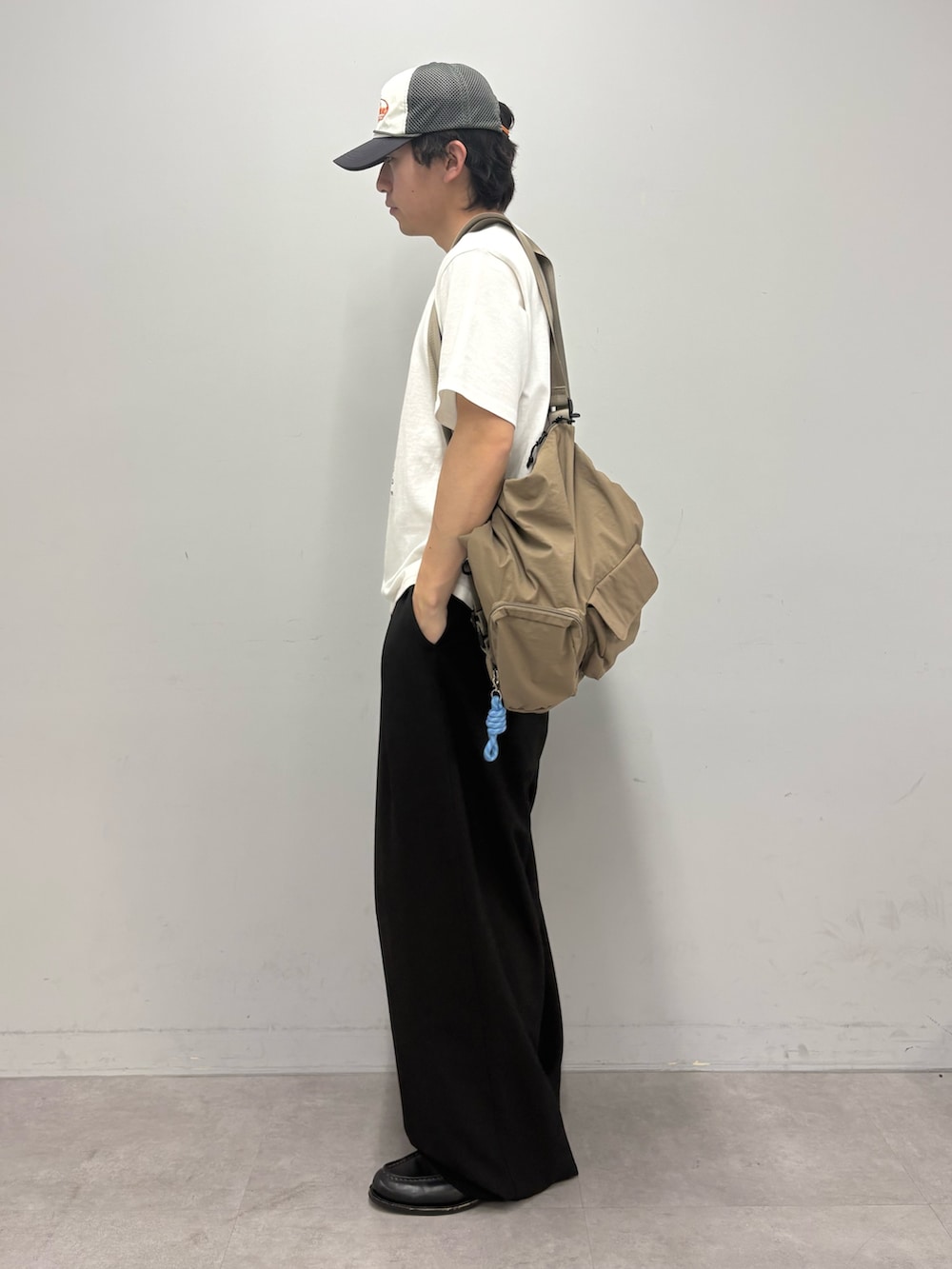 ホワイト系のTシャツ/カットソー、ベージュ系のトートバッグ、ブラック系のスラックスを着用したメンズの春コーディネートの2枚目の写真