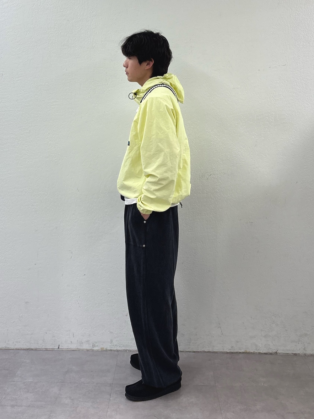 イエロー系のマウンテンパーカー、ブラック系のショルダーバッグ、ブラック系のスウェットパンツを着用したメンズの春コーディネートの2枚目の写真
