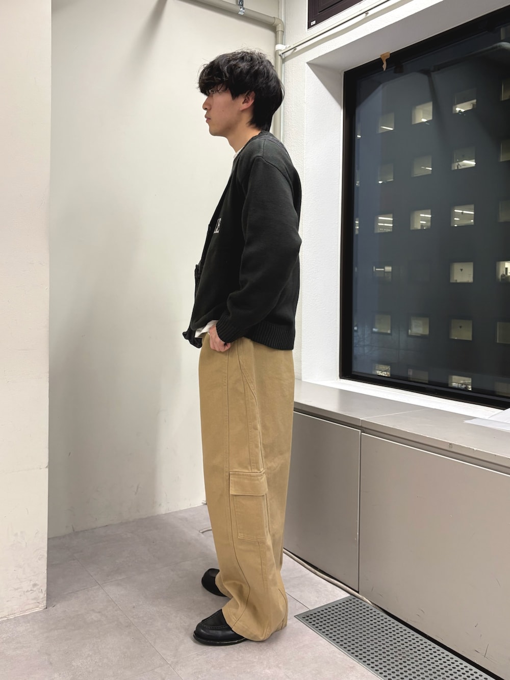 グレー系のニット/セーター、ブラック系のショルダーバッグ、ベージュ系のカーゴパンツを着用したメンズの冬コーディネートの2枚目の写真