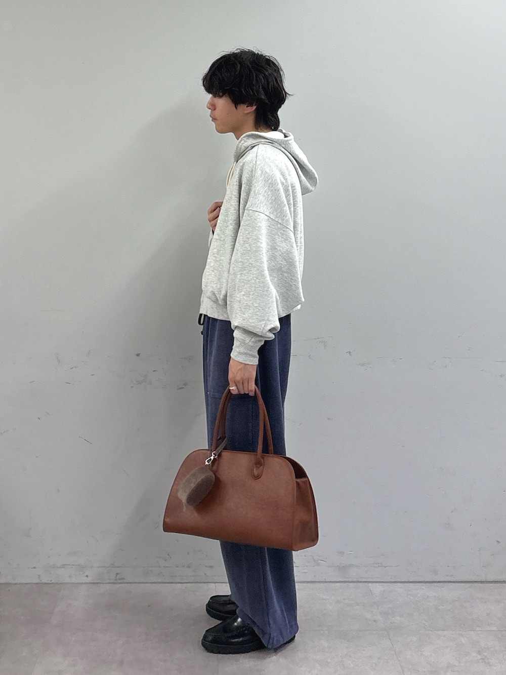 グレー系のパーカー、ブルー系のスウェットパンツ、イエロー系のトートバッグを着用したメンズの春コーディネートの2枚目の写真