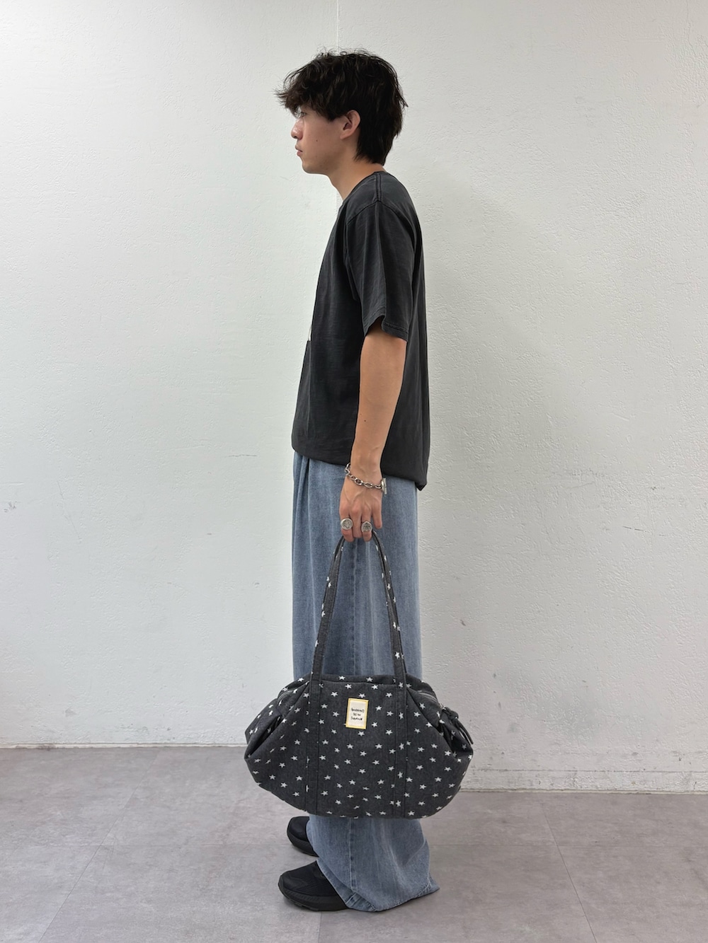 ブラック系のTシャツ/カットソー、ブルー系のデニムパンツ、グレー系のボストンバッグを着用したメンズの夏コーディネートの2枚目の写真