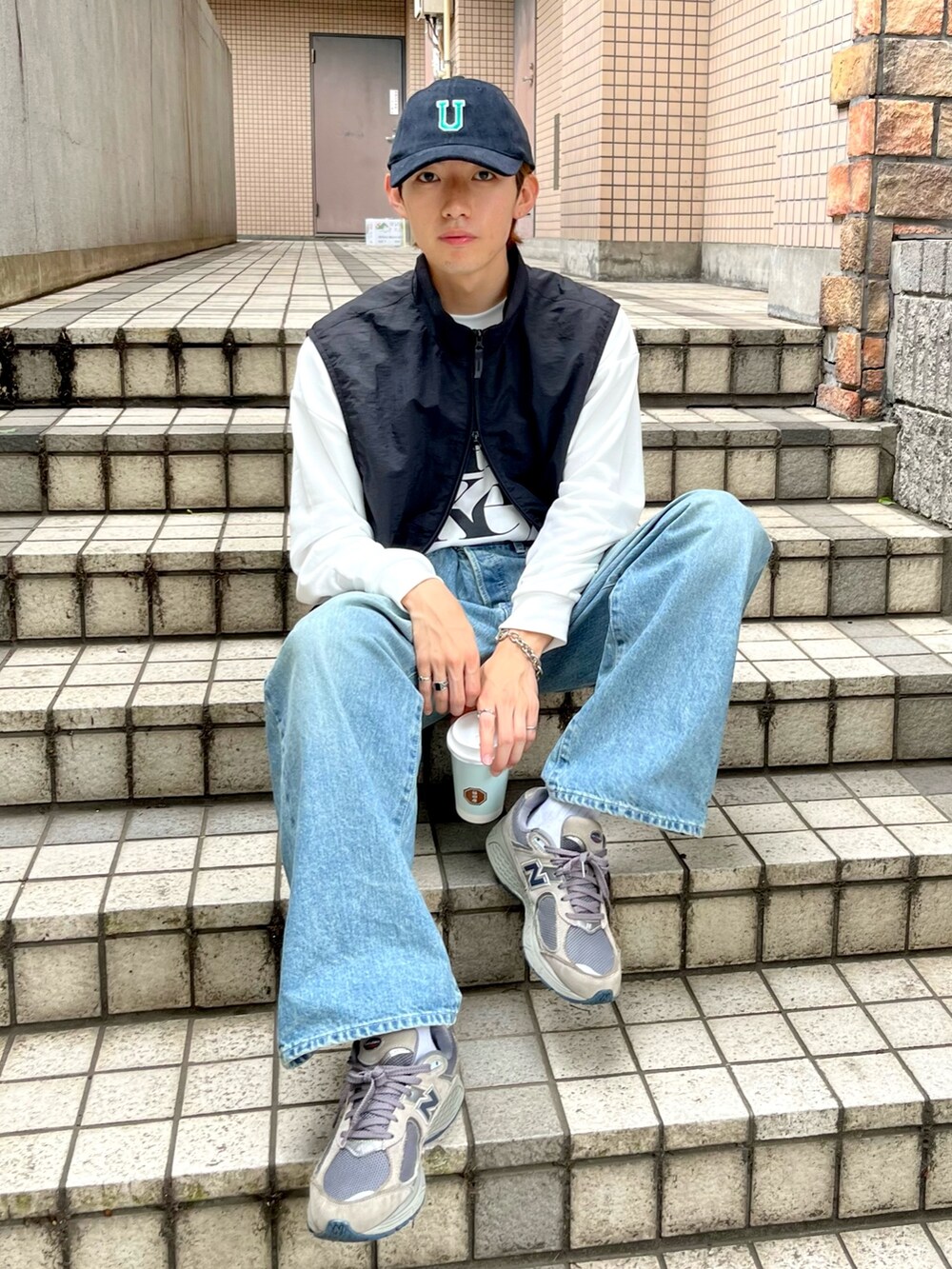 グレー系のスニーカー、ブルー系のデニムパンツ、ホワイト系のショルダーバッグを着用したメンズの秋コーディネートの2枚目の写真