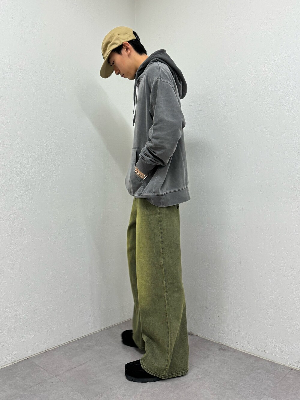 グレー系のパーカー、ブラウン系のデニムパンツ、ブラック系のスニーカーを着用したメンズの秋コーディネートの2枚目の写真