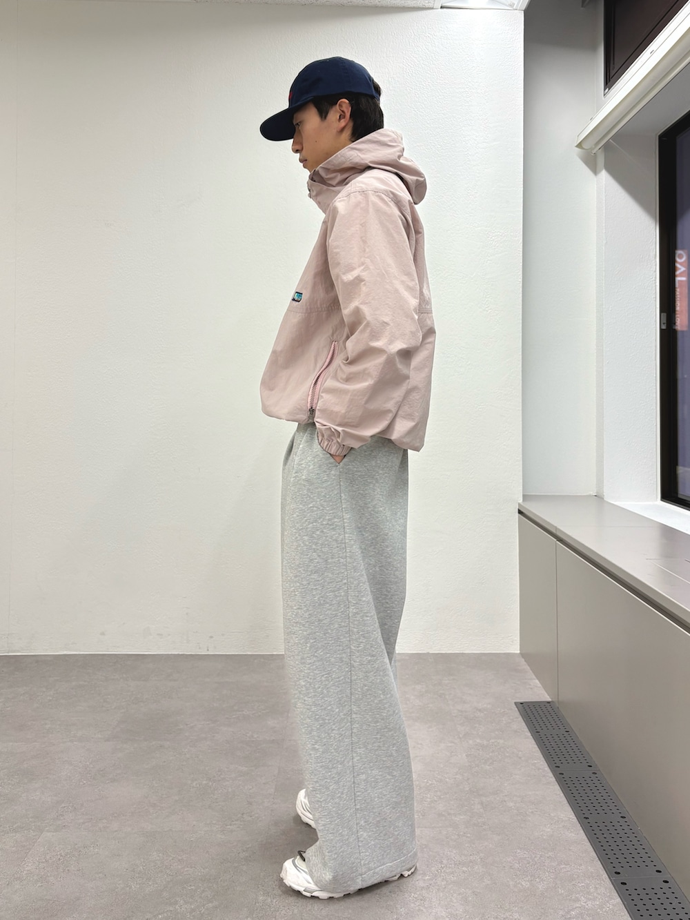 ピンク系のマウンテンパーカー、グレー系のその他パンツ、ブルー系のキャップを着用したメンズの冬コーディネートの2枚目の写真