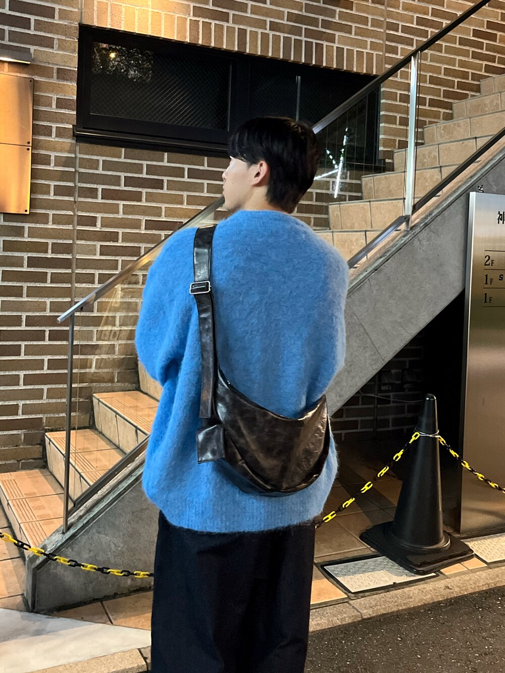 ブルー系のパンツ、ブルー系のニット/セーター、ブラック系のショルダーバッグを着用したメンズの秋コーディネートの3枚目の写真