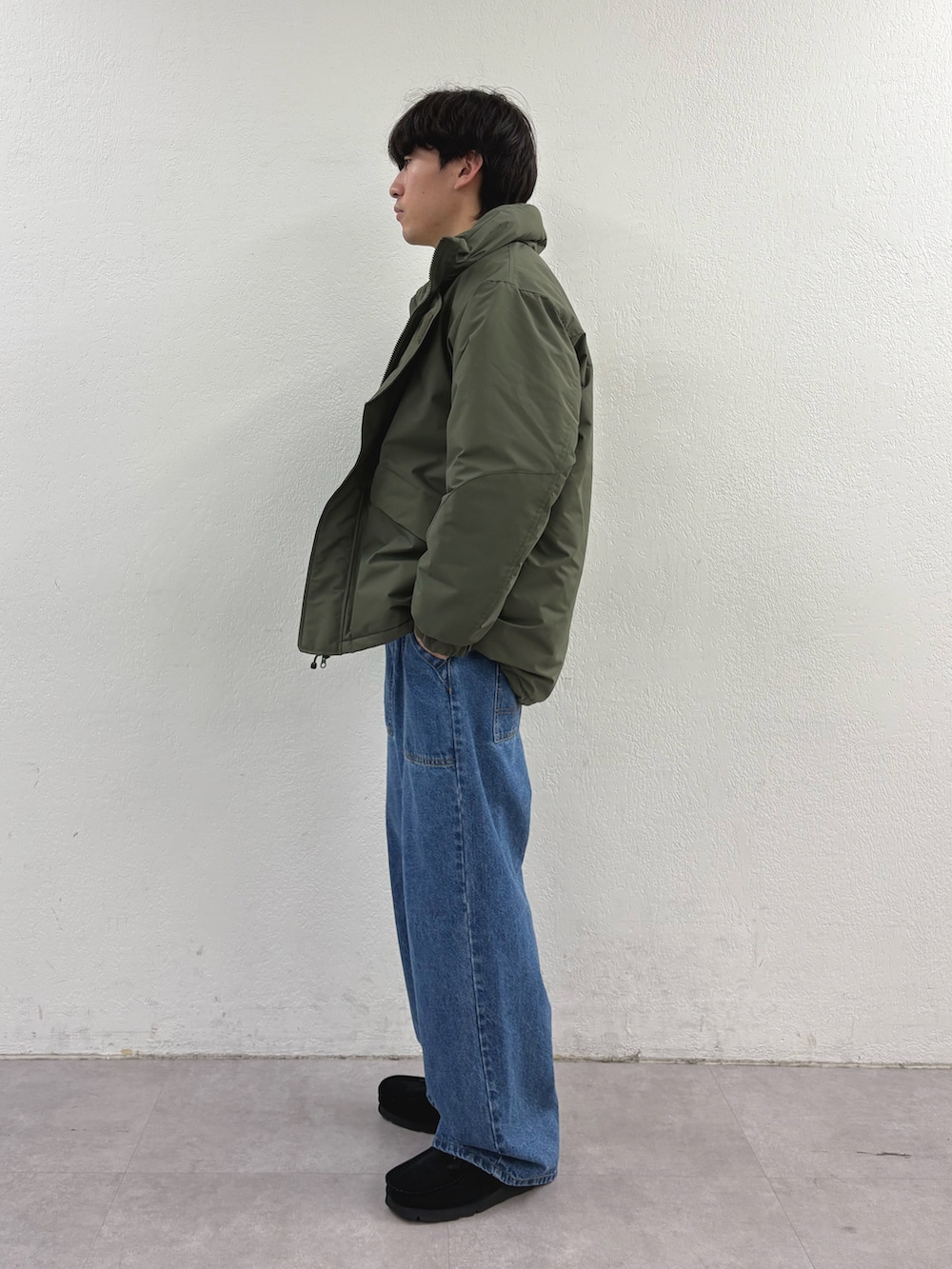 グリーン系のダウンジャケット/コート、ホワイト系のニット/セーター、ブルー系のデニムパンツを着用したメンズの冬コーディネートの2枚目の写真