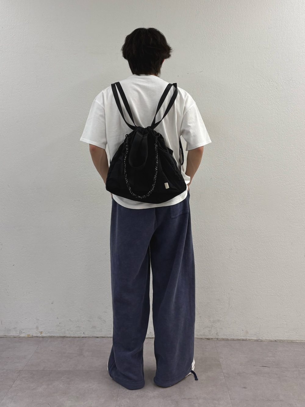 ホワイト系のTシャツ/カットソー、ブラック系のトートバッグ、ブルー系のスウェットパンツを着用したメンズの春コーディネートの3枚目の写真