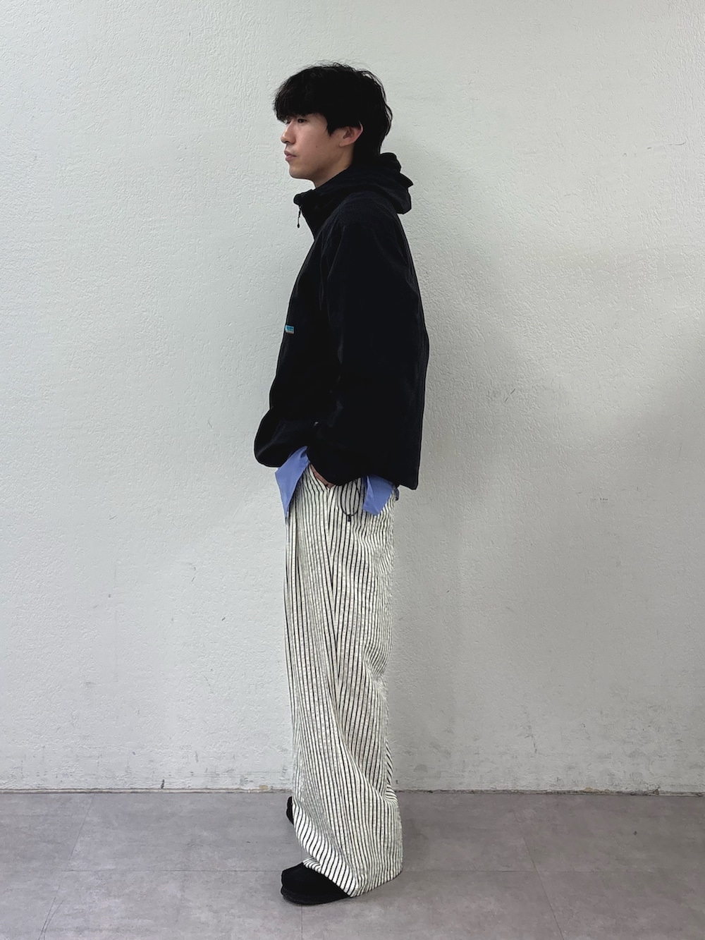 ブラック系のマウンテンパーカー、ブルー系のシャツ/ブラウス、ホワイト系のその他パンツを着用したメンズの春コーディネートの2枚目の写真