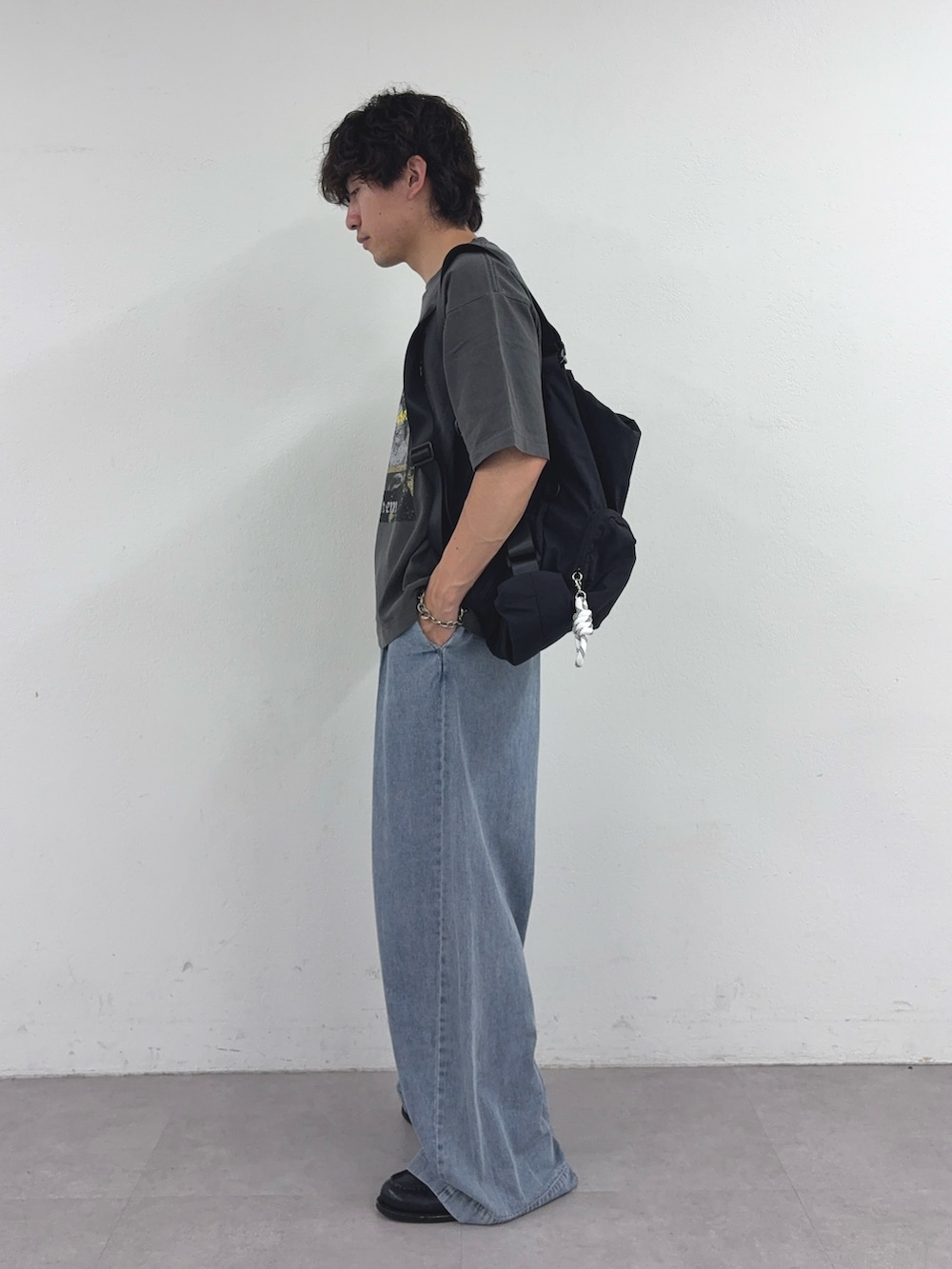ブラック系のTシャツ/カットソー、ブラック系のバックパック/リュック、ブルー系のデニムパンツを着用したメンズの春コーディネートの2枚目の写真