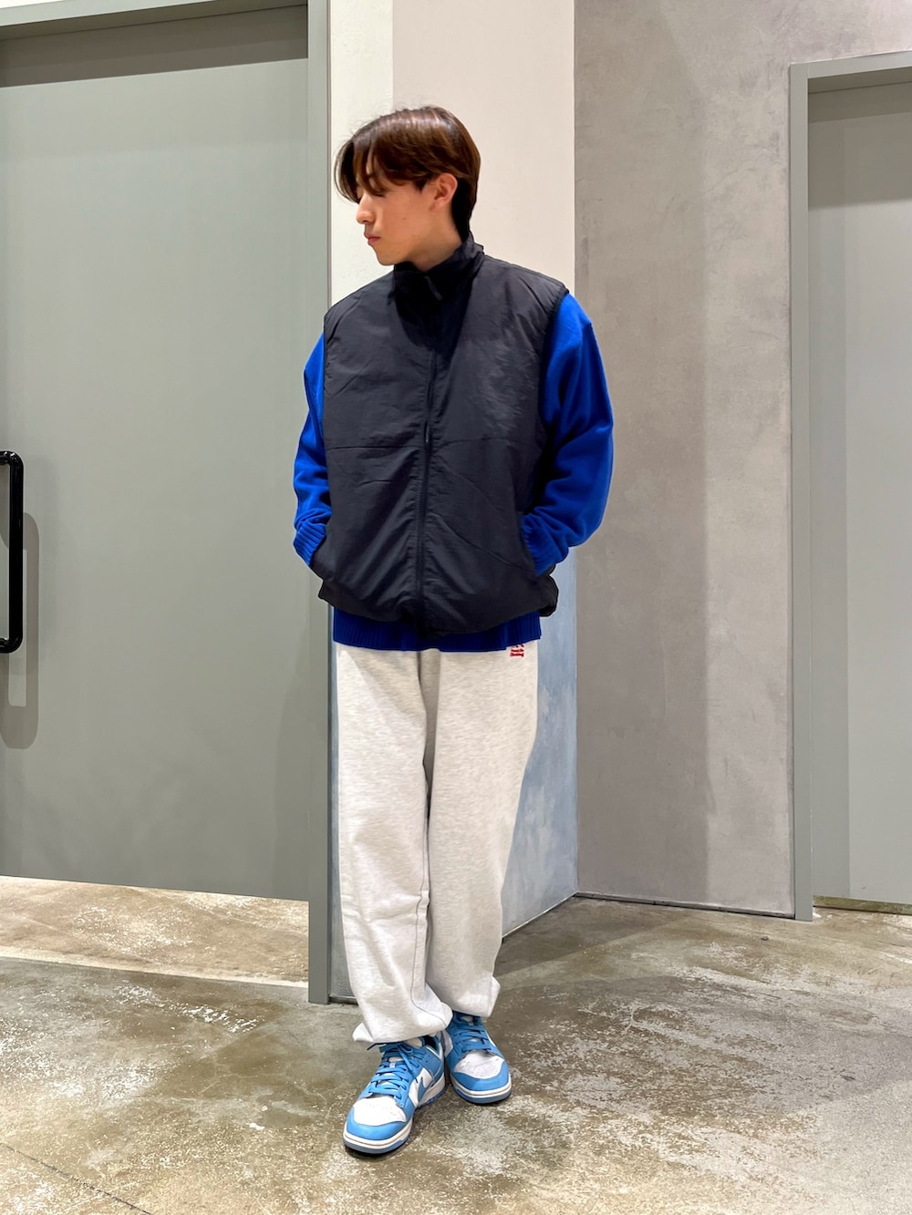 ブラック系のベスト、ブルー系のニット/セーター、グレー系のスウェットパンツを着用したメンズの冬コーディネートの2枚目の写真