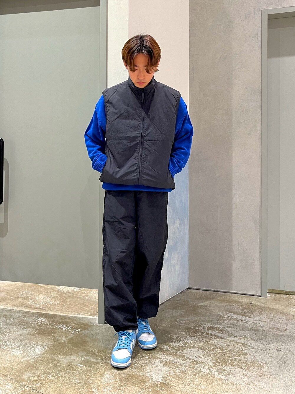 ブルー系のスニーカー、ブラック系のベスト、ブラック系のその他パンツを着用したメンズの冬コーディネートの2枚目の写真