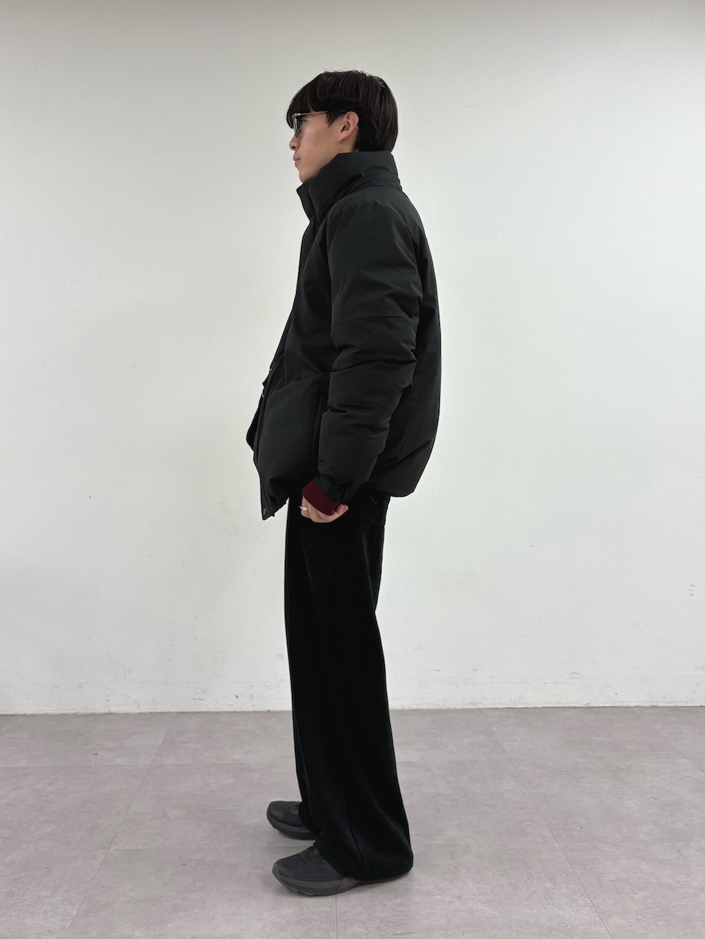 ブラック系のダウンジャケット/コート、レッド系のニット/セーター、ブラック系のショルダーバッグを着用したメンズの冬コーディネートの2枚目の写真