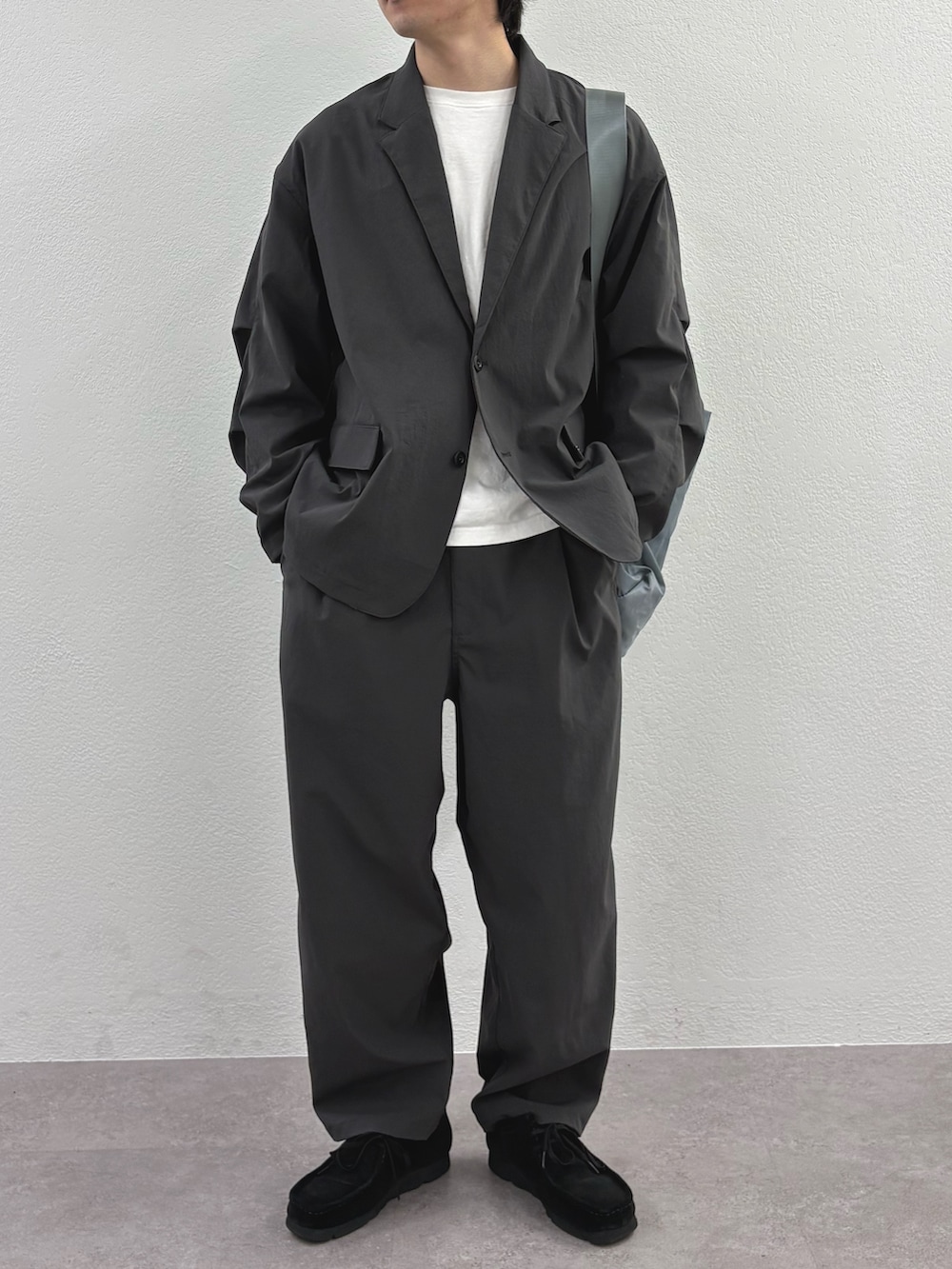 ブラック系のダウンジャケット/コート、グレー系のテーラードジャケット、ブラック系のショルダーバッグを着用したメンズの冬コーディネートの4枚目の写真