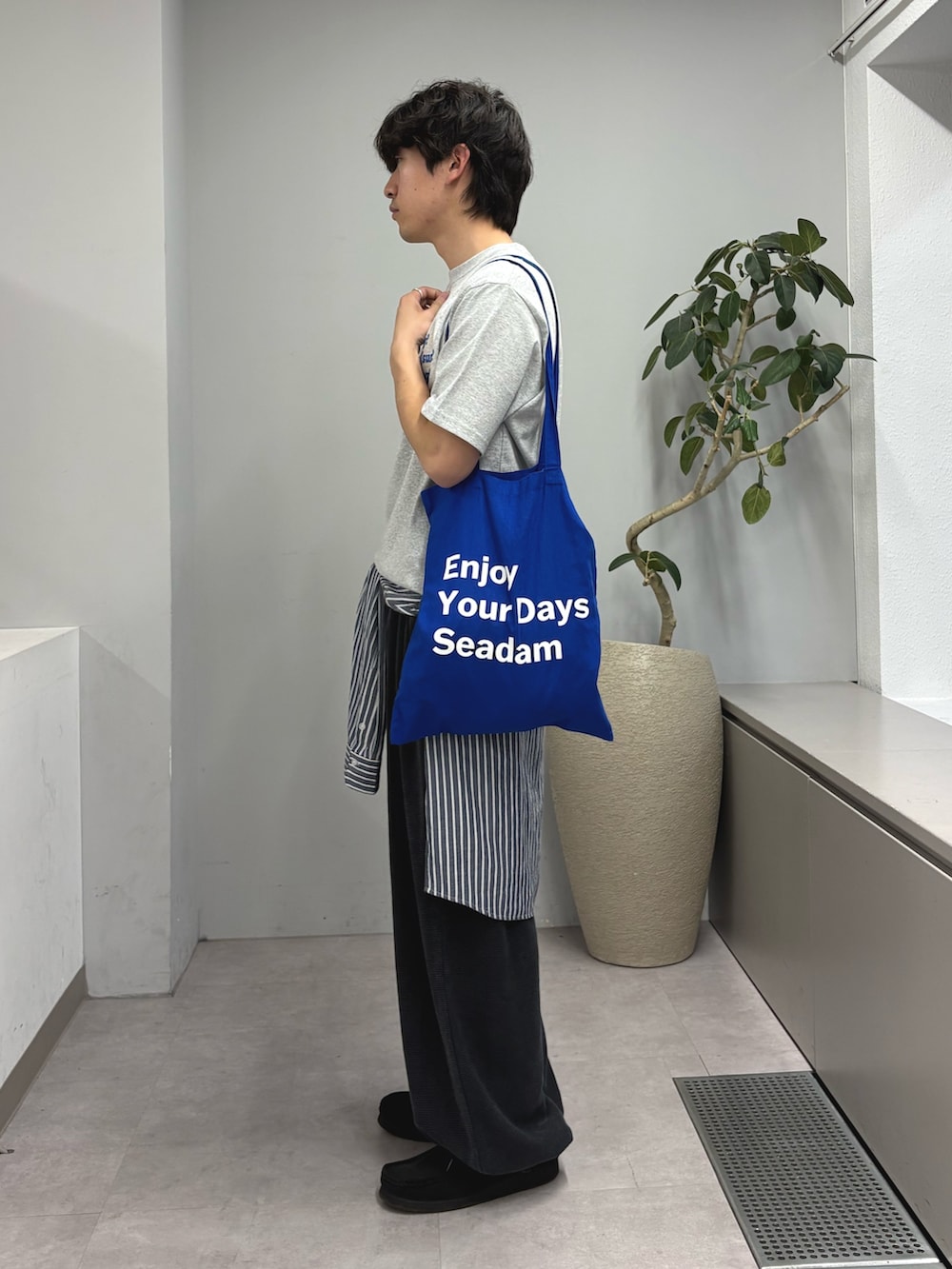 グレー系のTシャツ/カットソー、ブルー系のトートバッグ、ブラック系のスウェットパンツを着用したメンズの春コーディネートの2枚目の写真