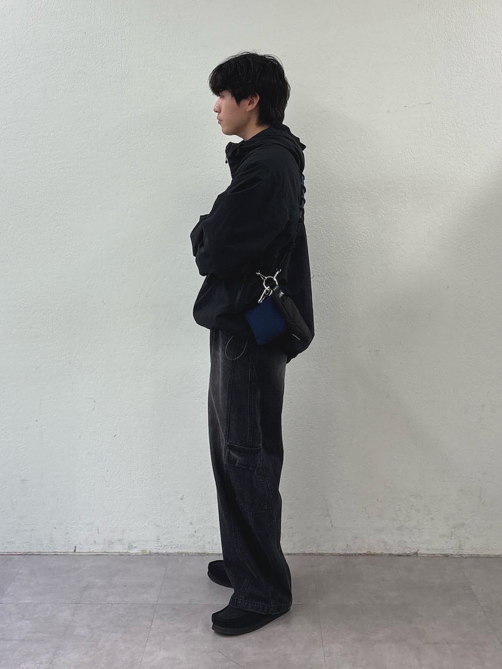 ブラック系のマウンテンパーカー、ブラック系のショルダーバッグ、ブラック系のカーゴパンツを着用したメンズの春コーディネートの2枚目の写真