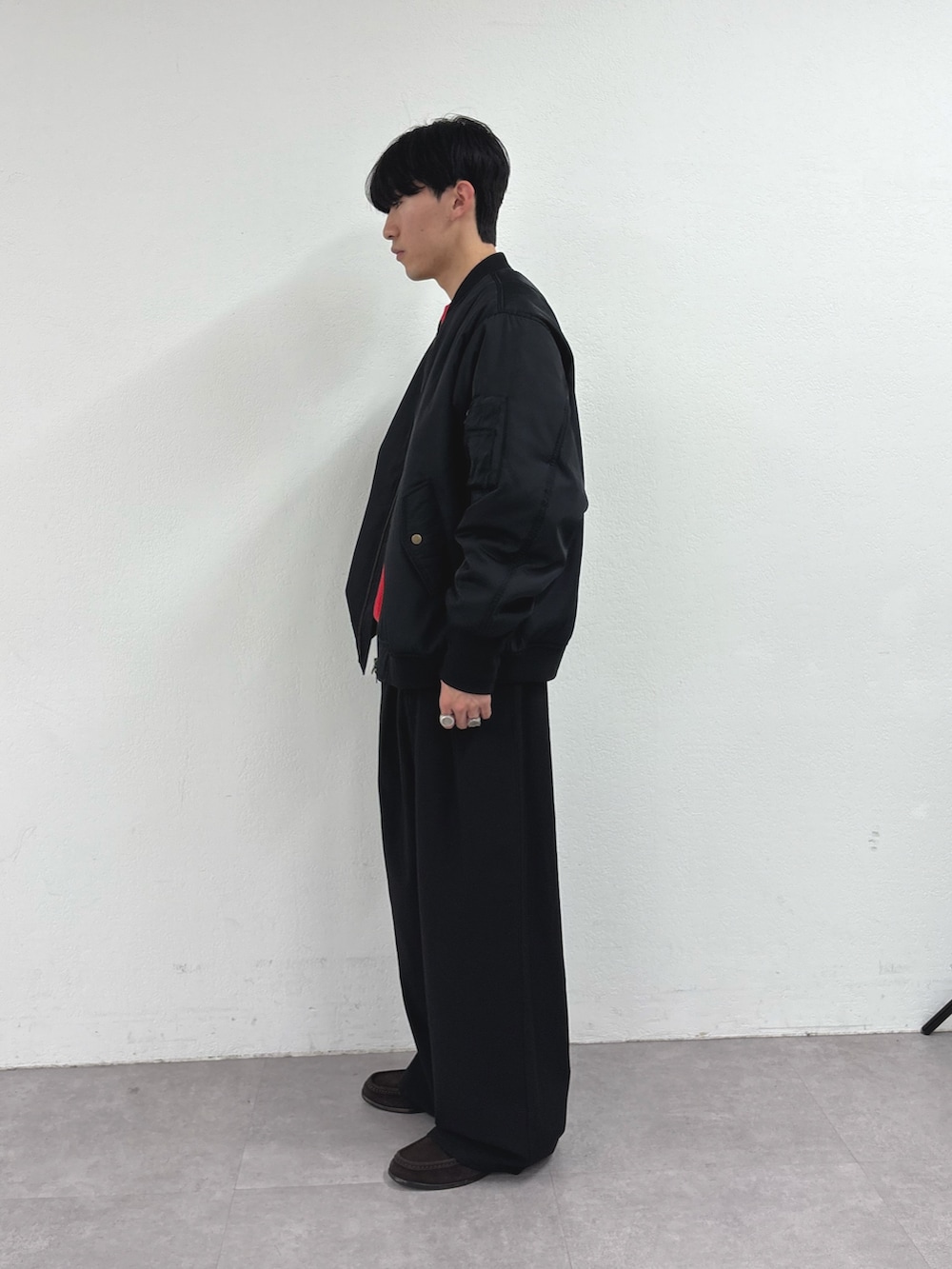 ブラック系のブルゾン、レッド系のニット/セーター、ブラック系のスラックスを着用したメンズの冬コーディネートの2枚目の写真