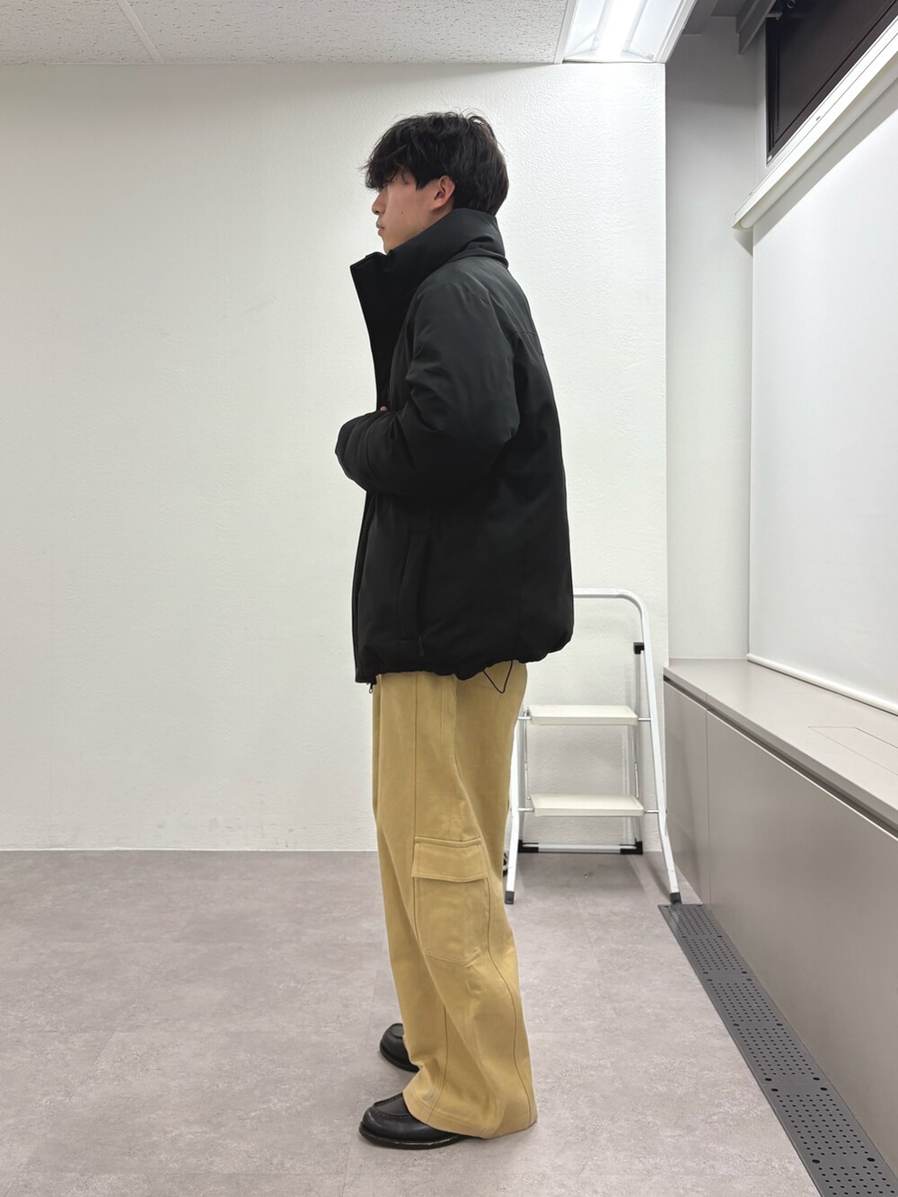 ブラック系のダウンジャケット/コート、ブルー系のニット/セーター、ベージュ系のカーゴパンツを着用したメンズの冬コーディネートの2枚目の写真