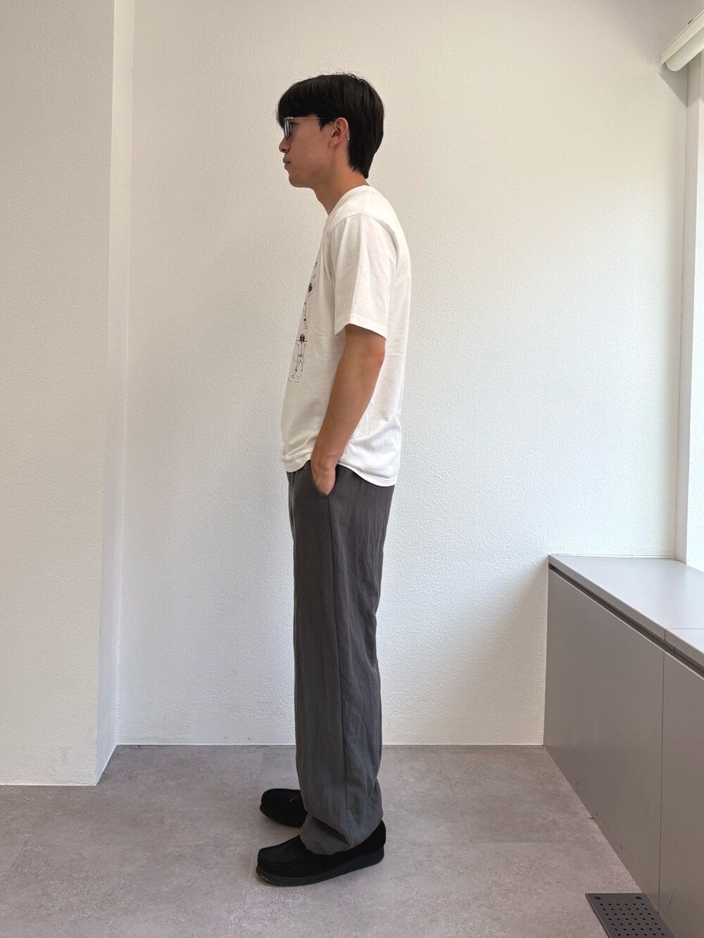 ホワイト系のTシャツ/カットソー、グレー系のスラックスを着用したメンズの夏コーディネートの2枚目の写真