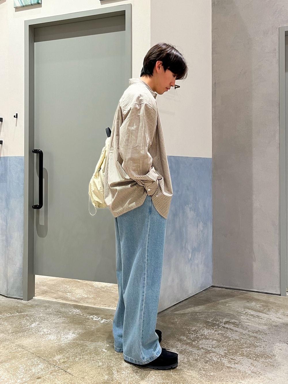 ブラック系のスニーカー、ブルー系のデニムパンツ、ベージュ系のシャツ/ブラウスを着用したメンズの春コーディネートの2枚目の写真