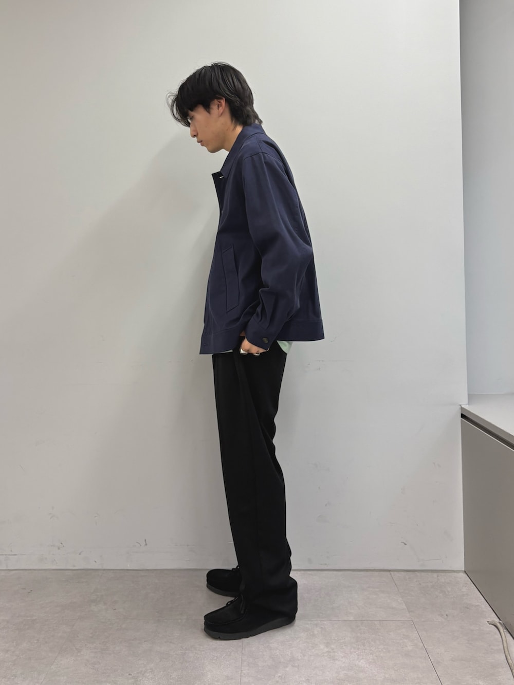 ブルー系のブルゾン、グリーン系のTシャツ/カットソー、ブラック系のスラックスを着用したメンズの春コーディネートの2枚目の写真