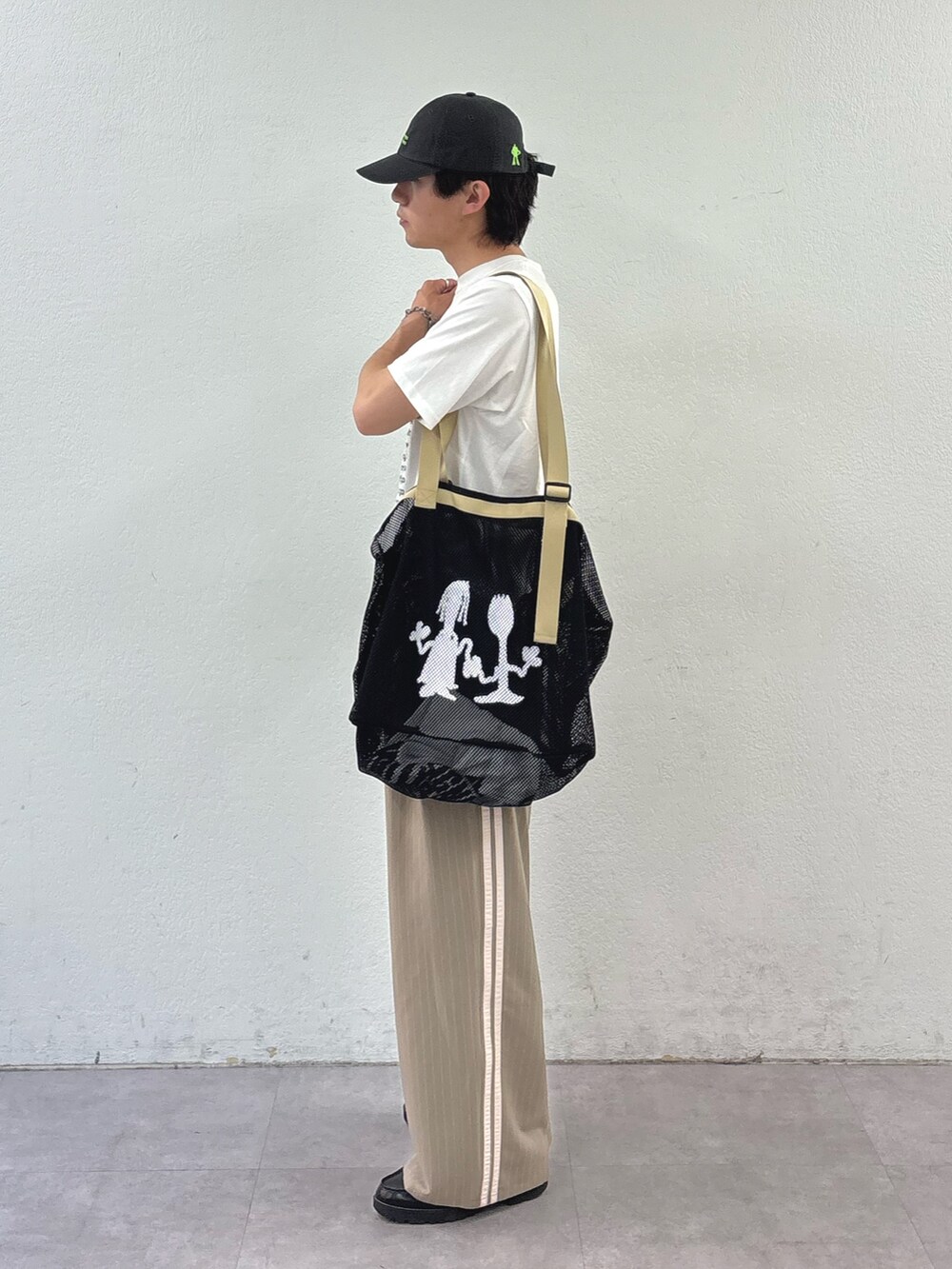 ホワイト系のTシャツ/カットソー、ブラック系のトートバッグ、ベージュ系のスラックスを着用したメンズの春コーディネートの2枚目の写真