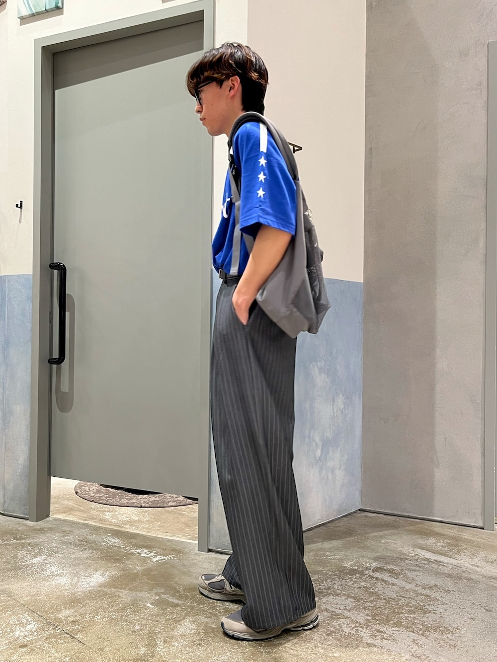 グレー系のスラックス、グレー系のスニーカー、ブルー系のTシャツ/カットソーを着用したメンズの夏コーディネートの2枚目の写真