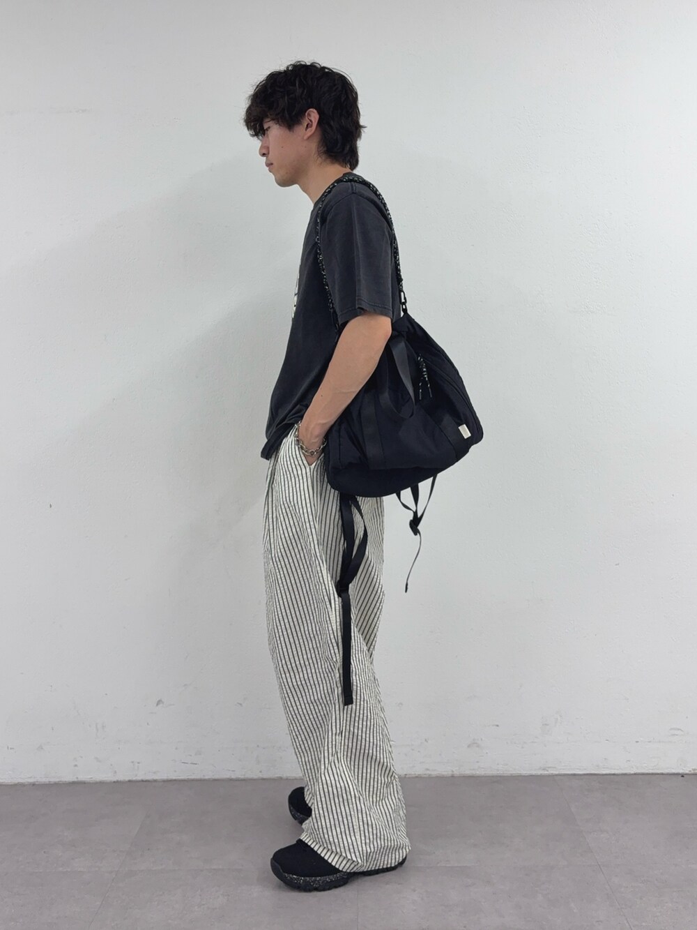 ブラック系のTシャツ/カットソー、ブラック系のトートバッグ、ホワイト系のその他パンツを着用したメンズの春コーディネートの2枚目の写真