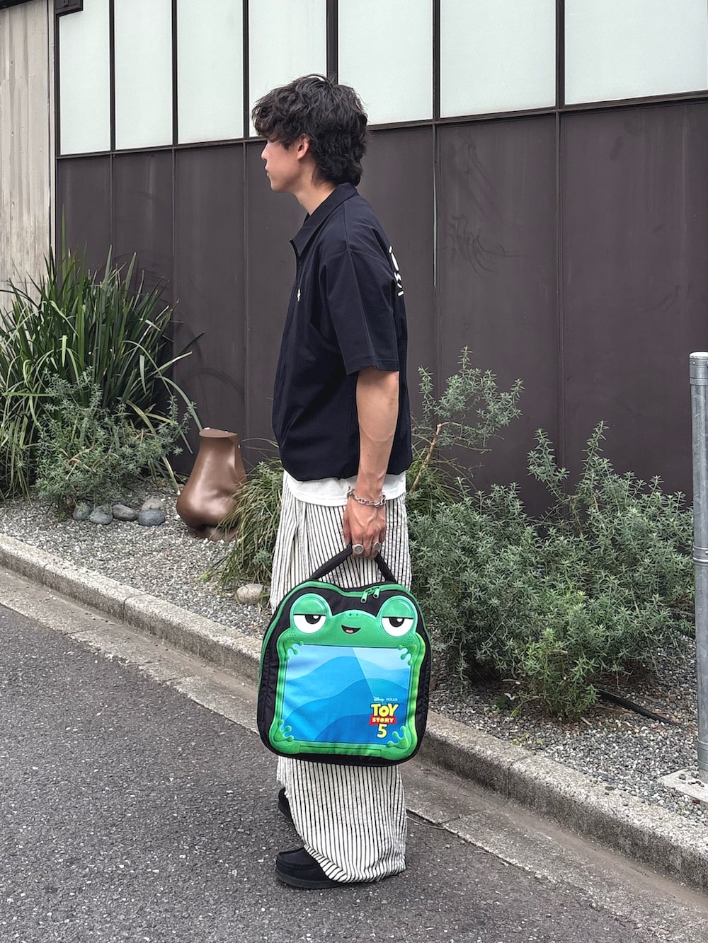 ブラック系のポロシャツ、ホワイト系のその他パンツ、ブラック系のPC・タブレットケースを着用したメンズの春コーディネートの2枚目の写真