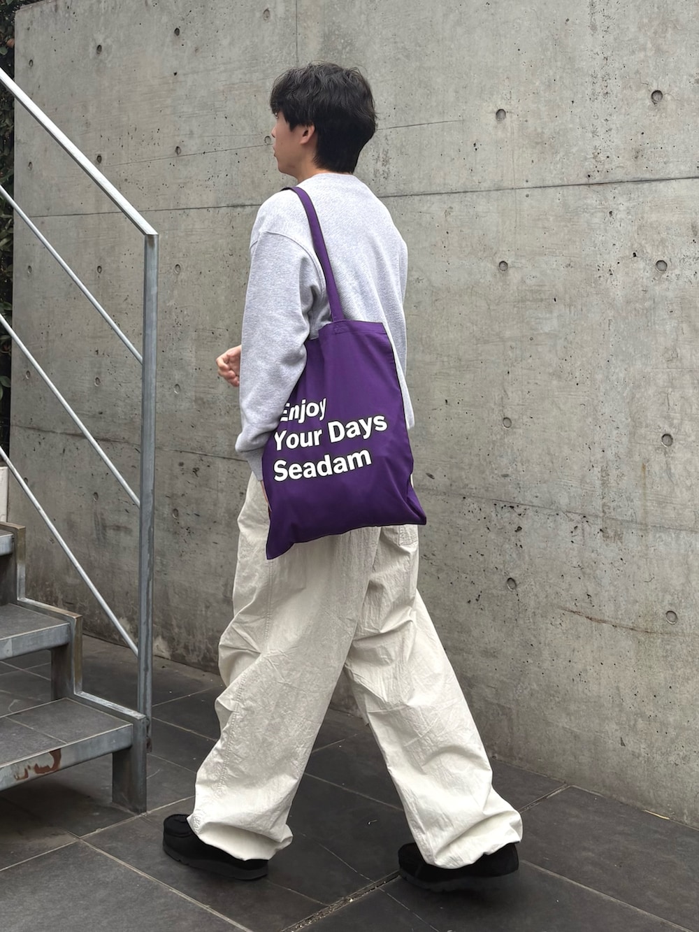 グレー系のスウェット、パープル系のトートバッグ、グレー系のカーゴパンツを着用したメンズの春コーディネートの2枚目の写真