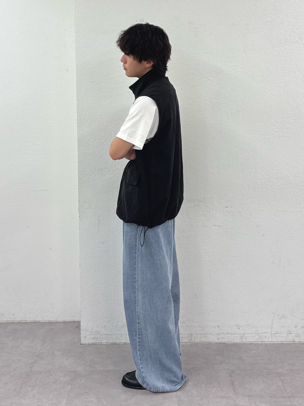 ブラック系のベスト、ホワイト系のTシャツ/カットソー、ブルー系のデニムパンツを着用したメンズの夏コーディネートの2枚目の写真