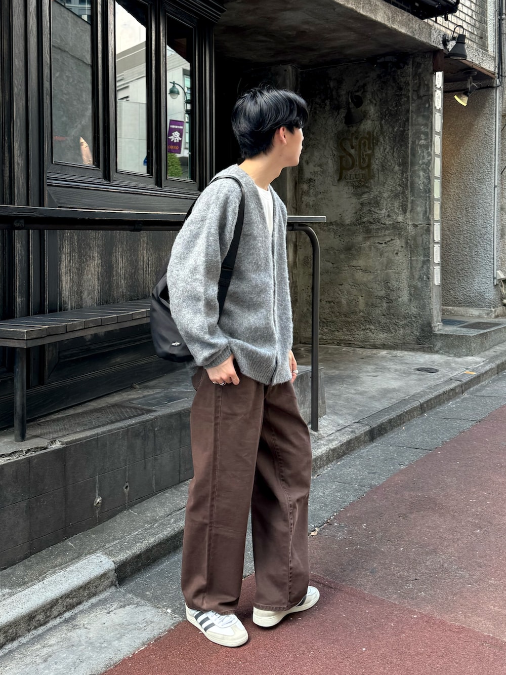 グレー系のカーディガン/ボレロ、ブラウン系のデニムパンツ、ブラック系のショルダーバッグを着用したメンズの秋コーディネートの2枚目の写真