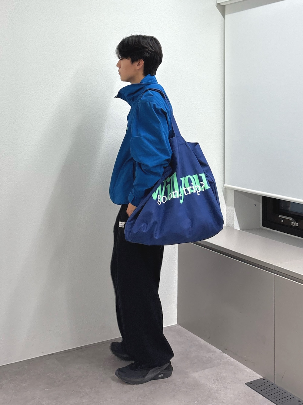 ブルー系のトートバッグ、ブルー系のナイロンジャケット、ブラック系のスウェットパンツを着用したメンズの秋コーディネートの2枚目の写真