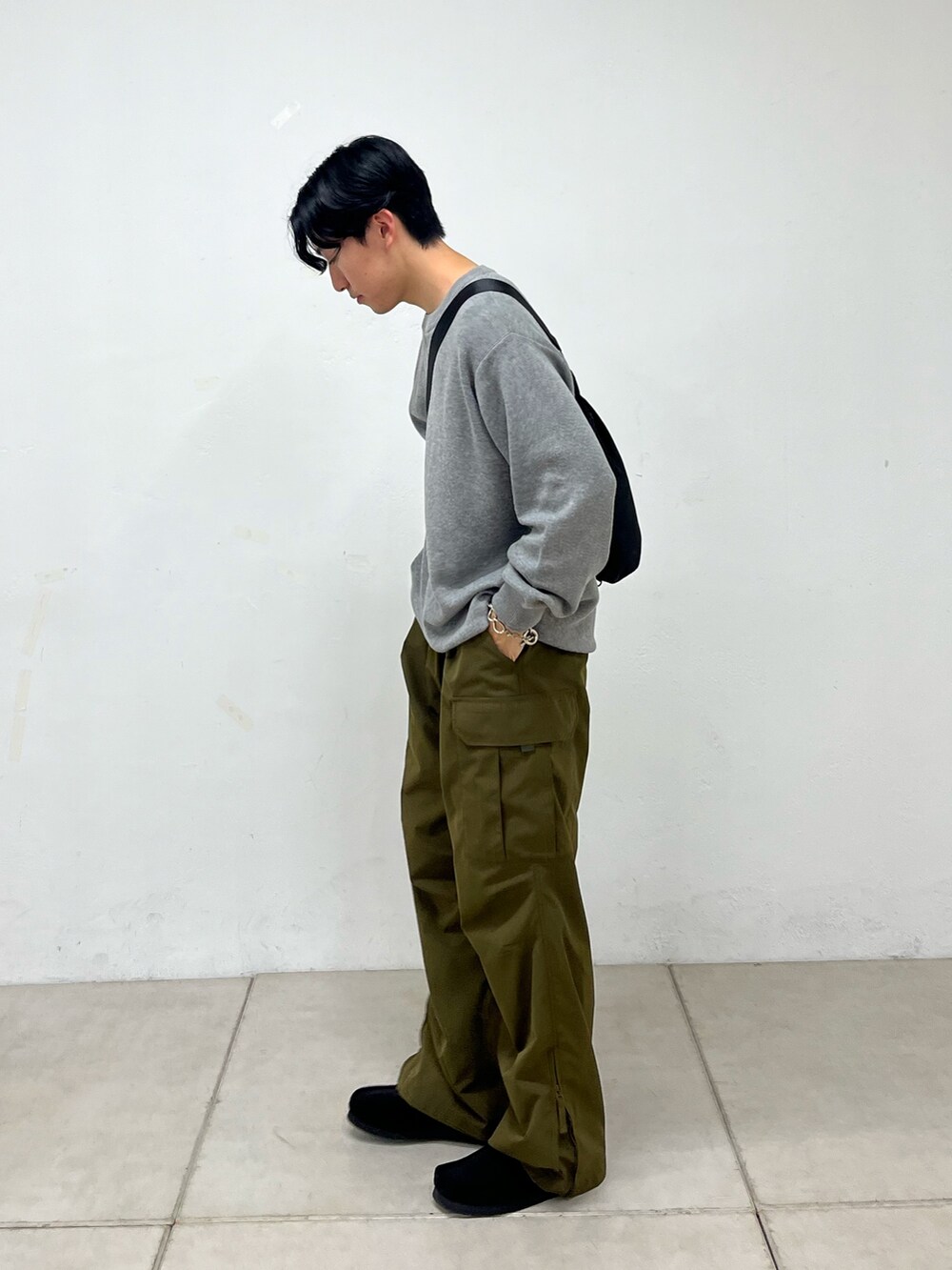グリーン系のカーゴパンツ、グレー系のニット/セーター、ブラック系のスニーカーを着用したメンズの秋コーディネートの2枚目の写真