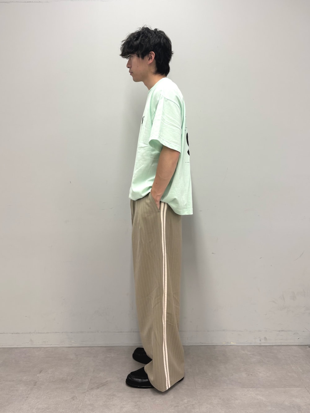 グリーン系のTシャツ/カットソー、ベージュ系のスラックスを着用したメンズの春コーディネートの2枚目の写真