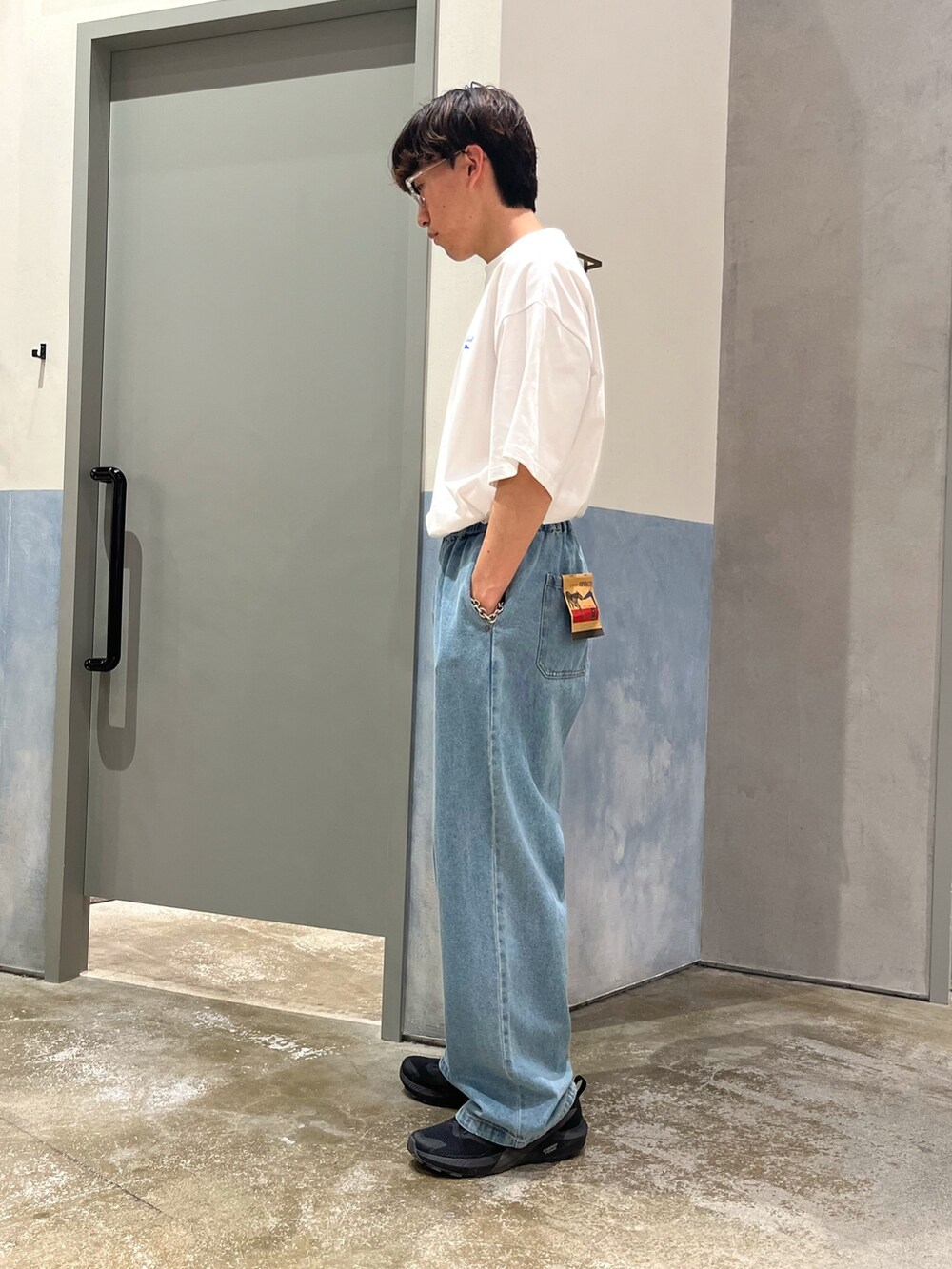 ブラック系のスニーカー、ブルー系のデニムパンツ、ホワイト系のTシャツ/カットソーを着用したメンズの春コーディネートの2枚目の写真