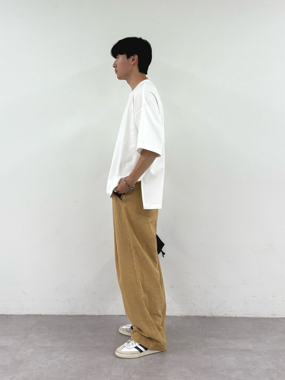 ホワイト系のTシャツ/カットソー、ベージュ系のチノパンツ、ブラック系のショルダーバッグを着用したメンズの夏コーディネートの2枚目の写真