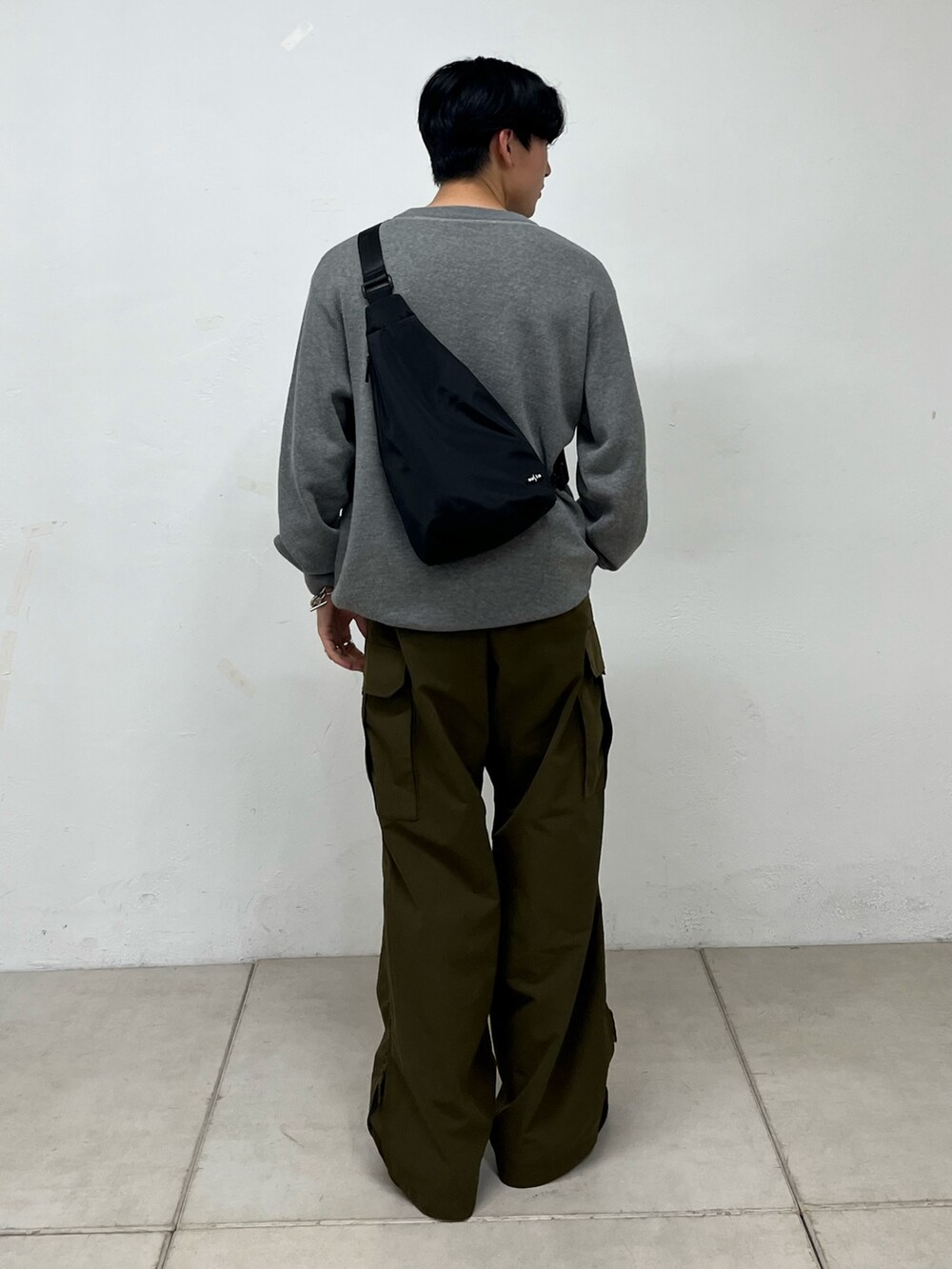 グリーン系のカーゴパンツ、グレー系のニット/セーター、ブラック系のスニーカーを着用したメンズの秋コーディネートの3枚目の写真