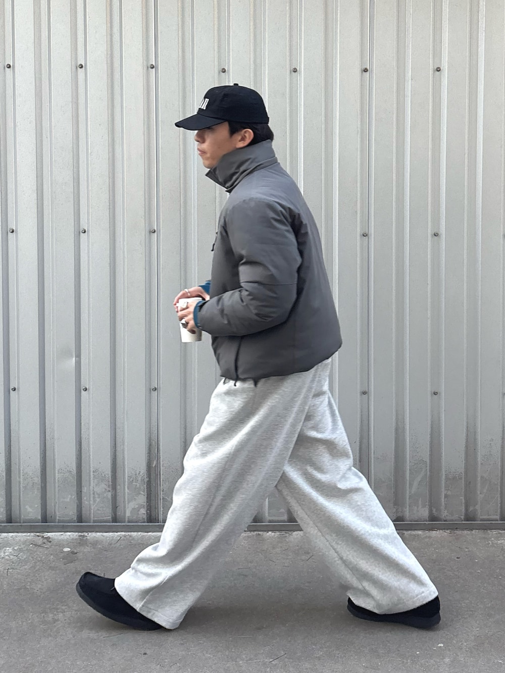 グレー系のダウンジャケット/コート、グレー系のその他パンツ、ブラック系のキャップを着用したメンズの冬コーディネートの2枚目の写真