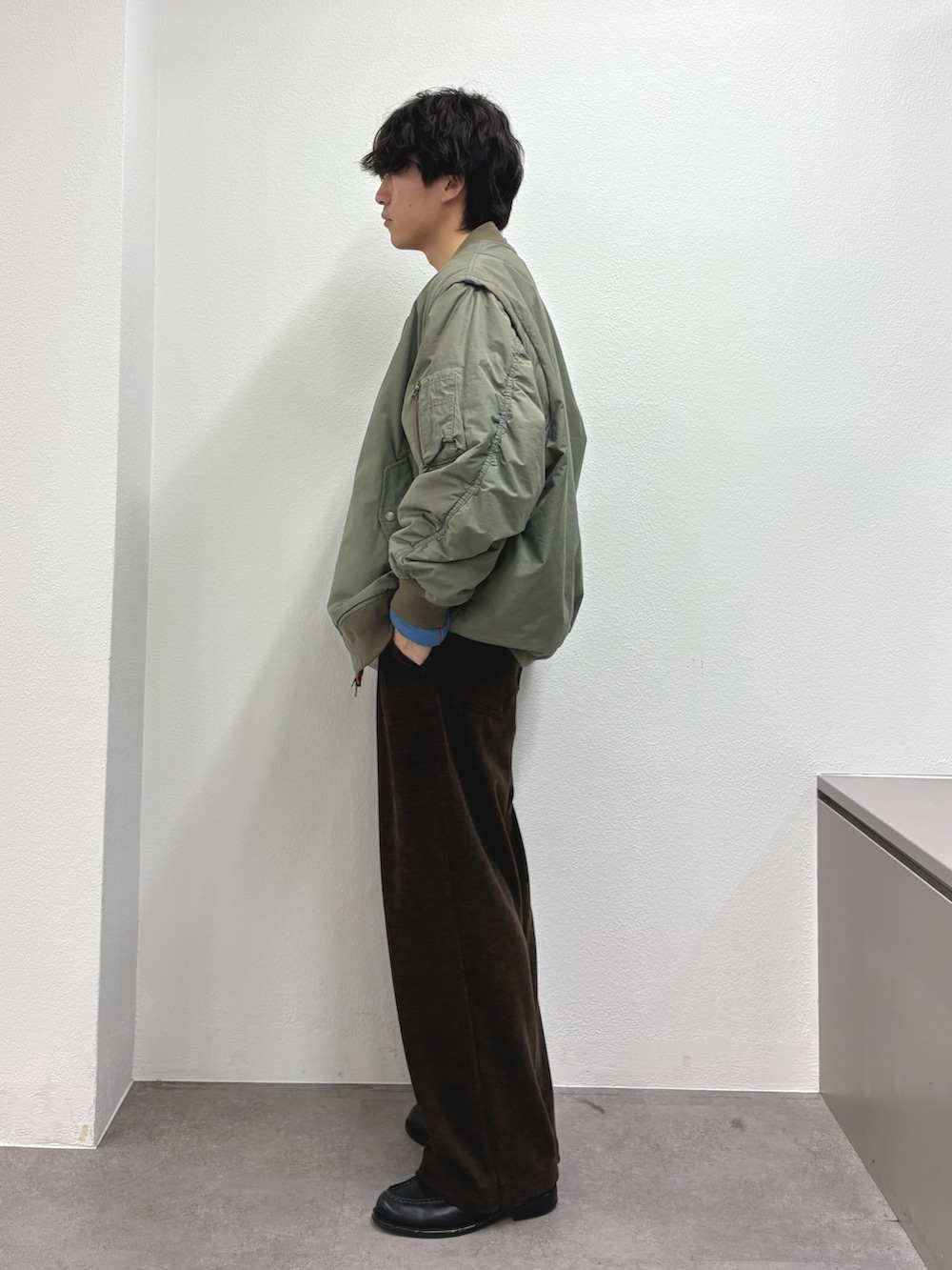 グリーン系のMA-1、レッド系のニット/セーター、ブラウン系のその他パンツを着用したメンズの冬コーディネートの2枚目の写真