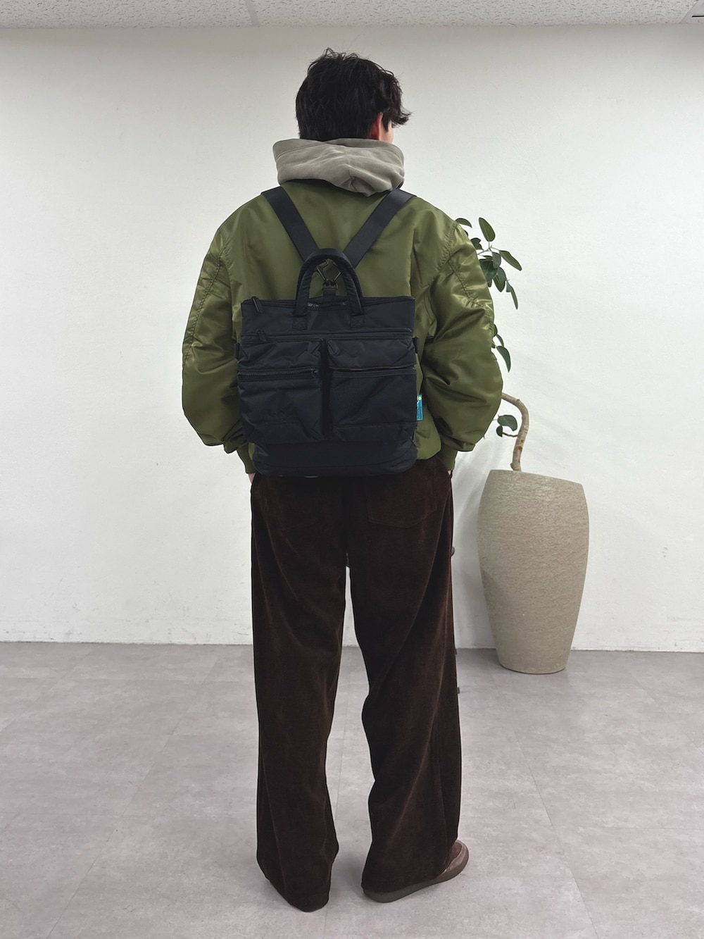 グリーン系のMA-1、ベージュ系のパーカー、ブラック系のショルダーバッグを着用したメンズの冬コーディネートの2枚目の写真