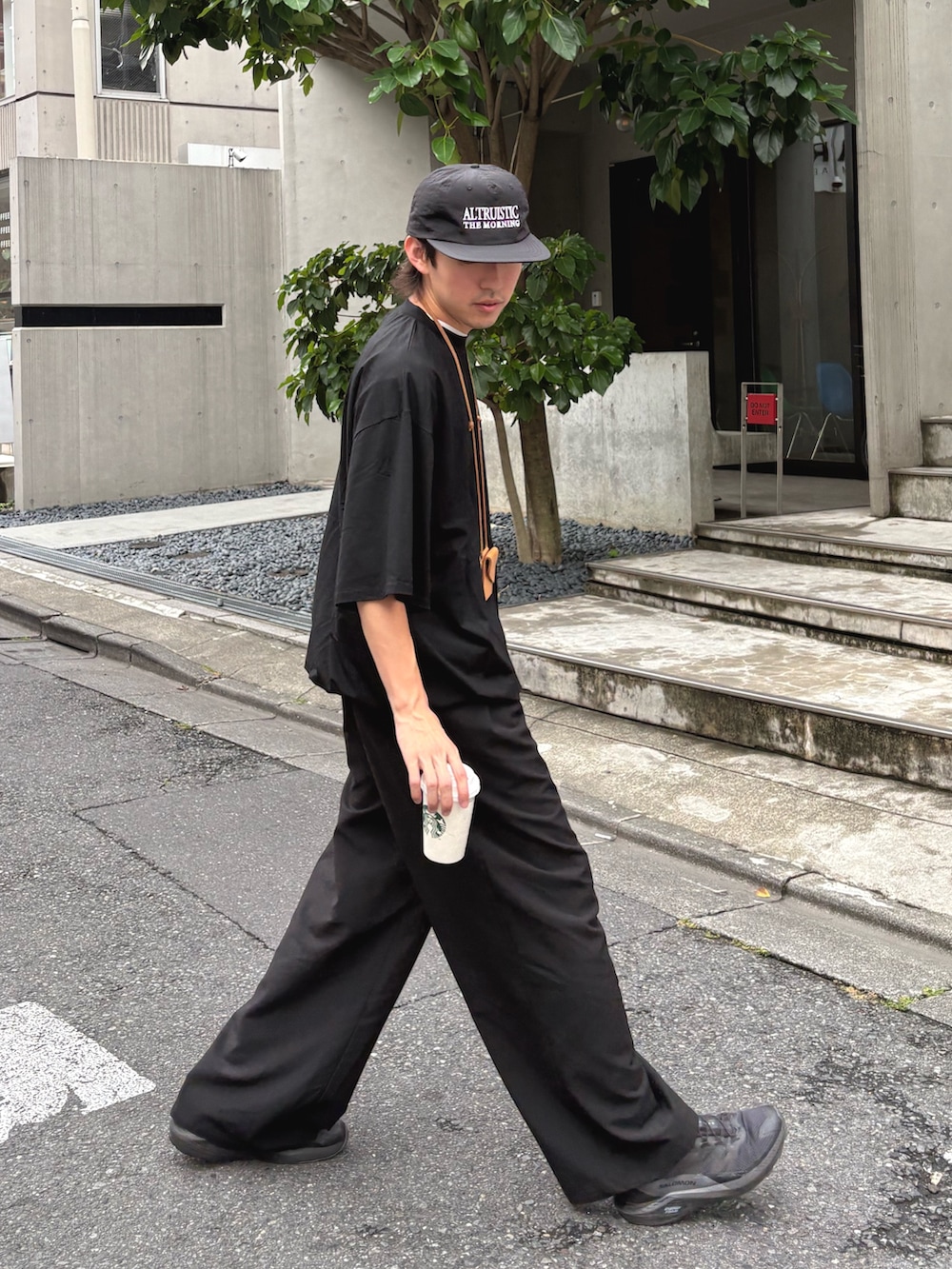 ブラック系のTシャツ/カットソー、ブラック系のスラックス、ブラック系のハットを着用したメンズの夏コーディネートの2枚目の写真