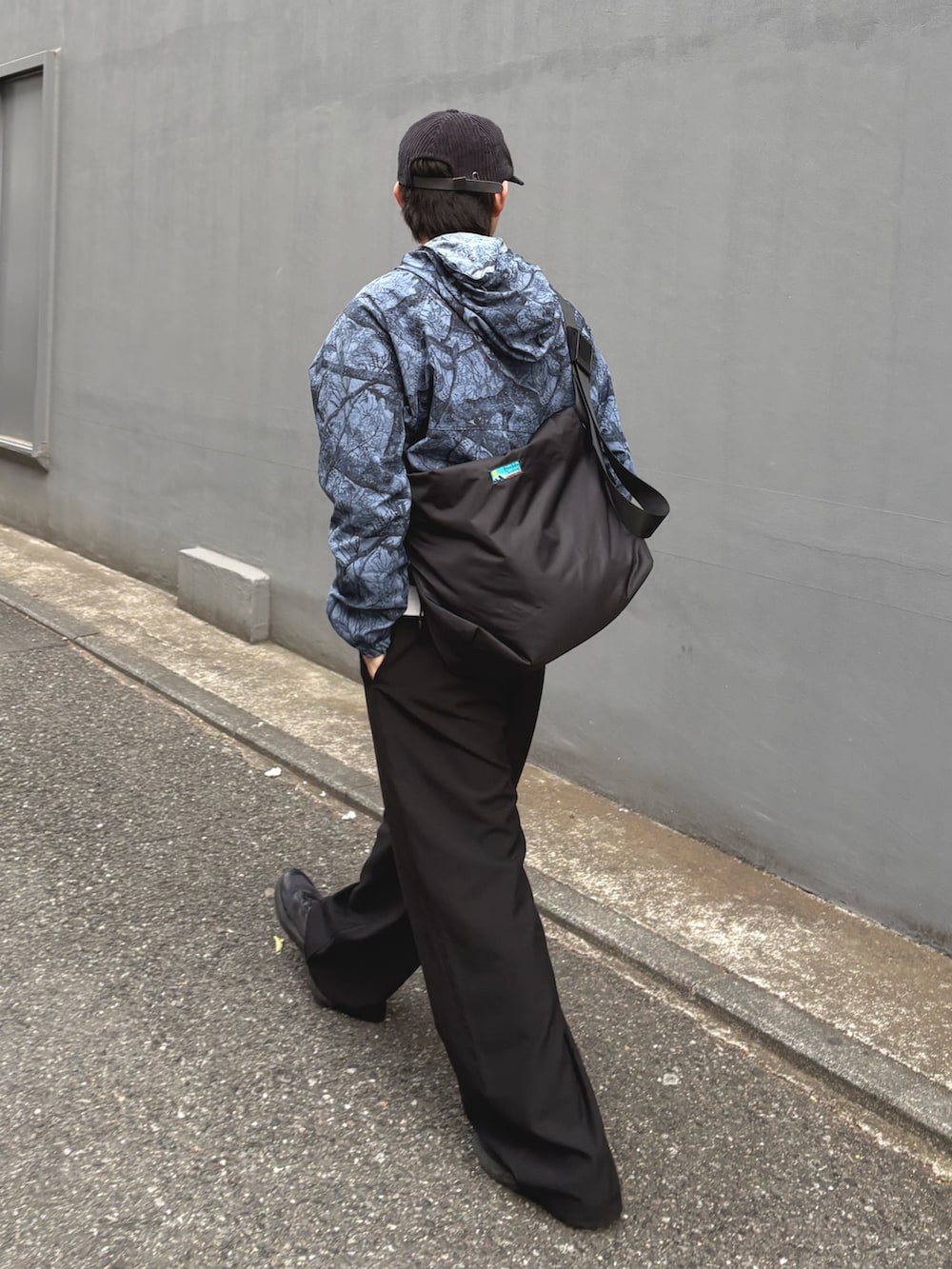 ブルー系のパーカー、ブラック系のショルダーバッグ、ブラック系のスラックスを着用したメンズの冬コーディネートの2枚目の写真