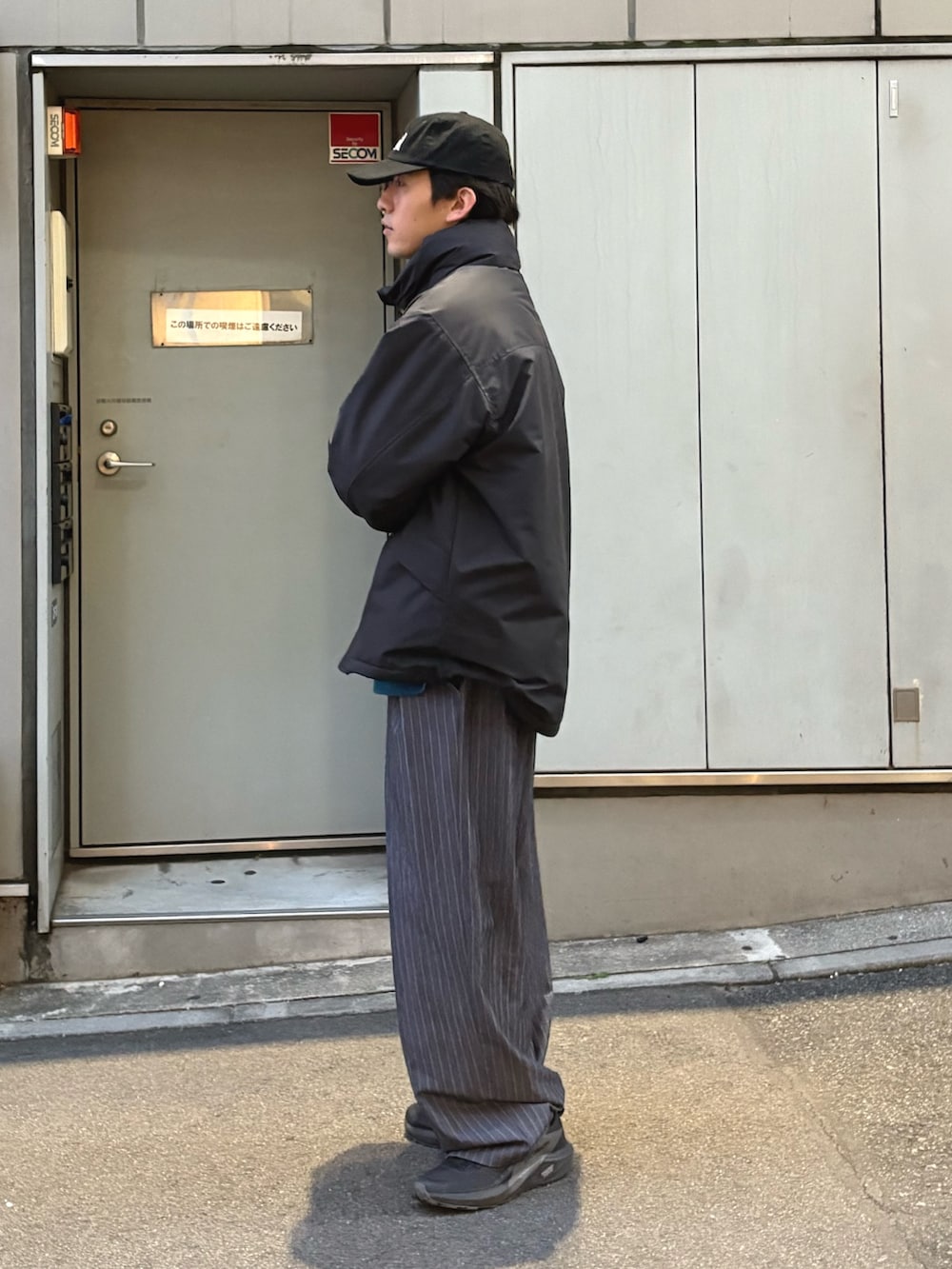 ブラック系のダウンジャケット/コート、ブルー系のニット/セーター、グレー系のスラックスを着用したメンズの秋コーディネートの2枚目の写真